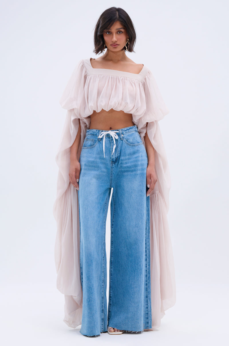 A woman faces forward wearing a sheer SLOUCHY SQUARE NECK LONG SLEEVE BLOUSE TOP with billowy sleeves and high-waisted, wide-leg blue jeans tied with a white drawstring, set against a plain white background.
