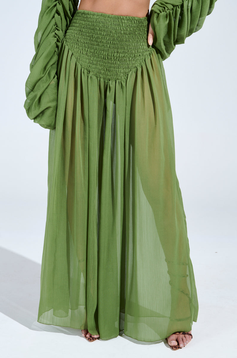A person wearing the LAURA Ruched Palazzo Pant in green with a smocked waistband and sheer, flowing design creates an elegant wide-leg silhouette that's effortlessly stylish and modern, ideal for refreshing any Spring wardrobe.