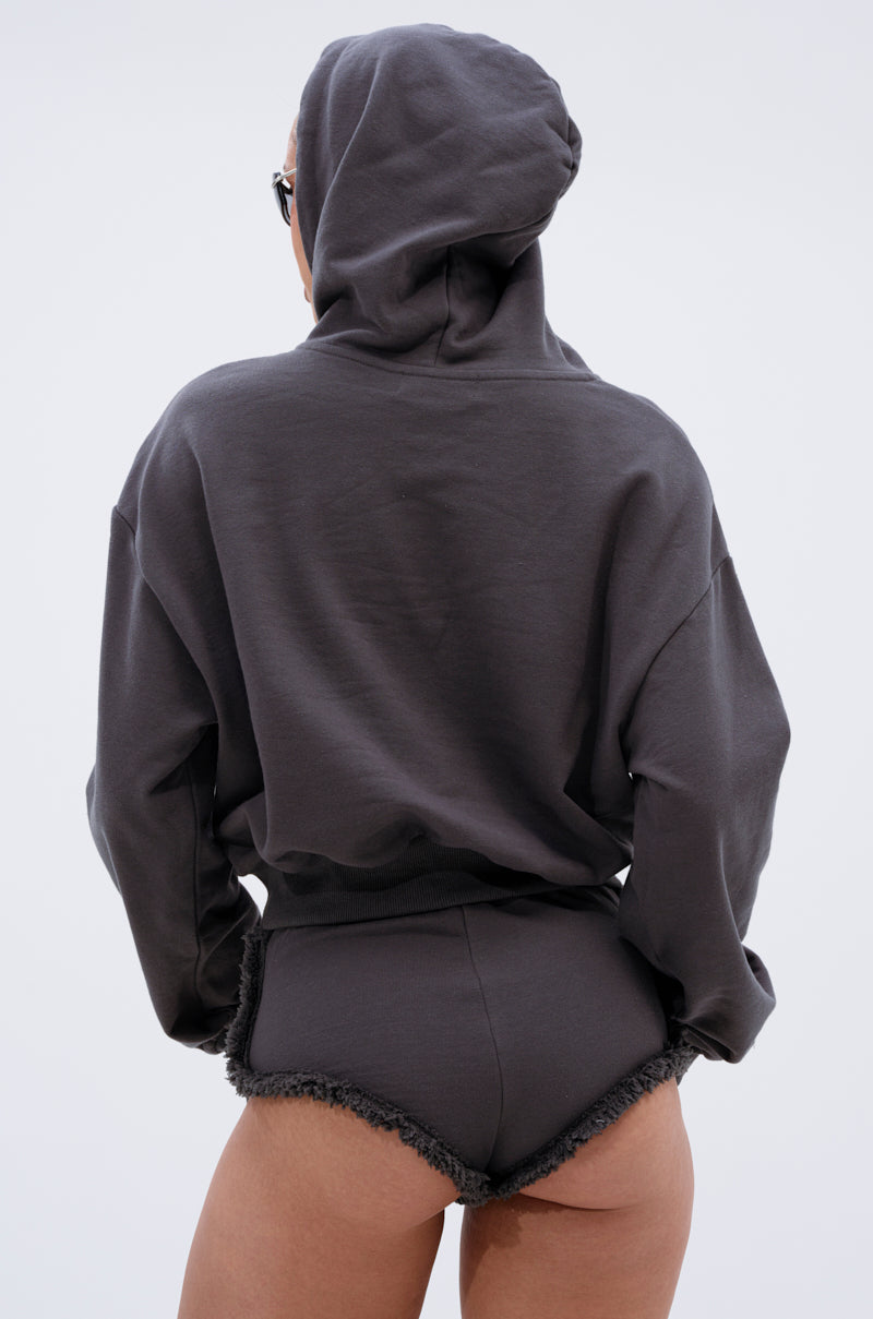 A person is seen from the back wearing the STRESSED AND DISTRESSED SWEATSHIRT, a dark cropped hoodie with a lace-up front, paired with matching high-waisted frayed shorts against a plain light background. 4