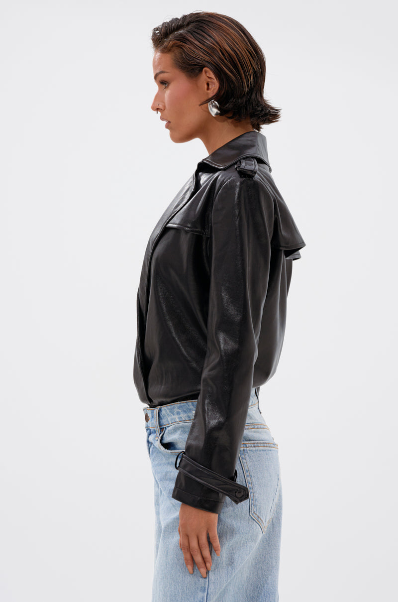 A woman with short dark hair models the TRACIE FAUX LEATHER BLAZER BODYSUIT paired with light blue jeans, standing in profile against a plain white background. 3