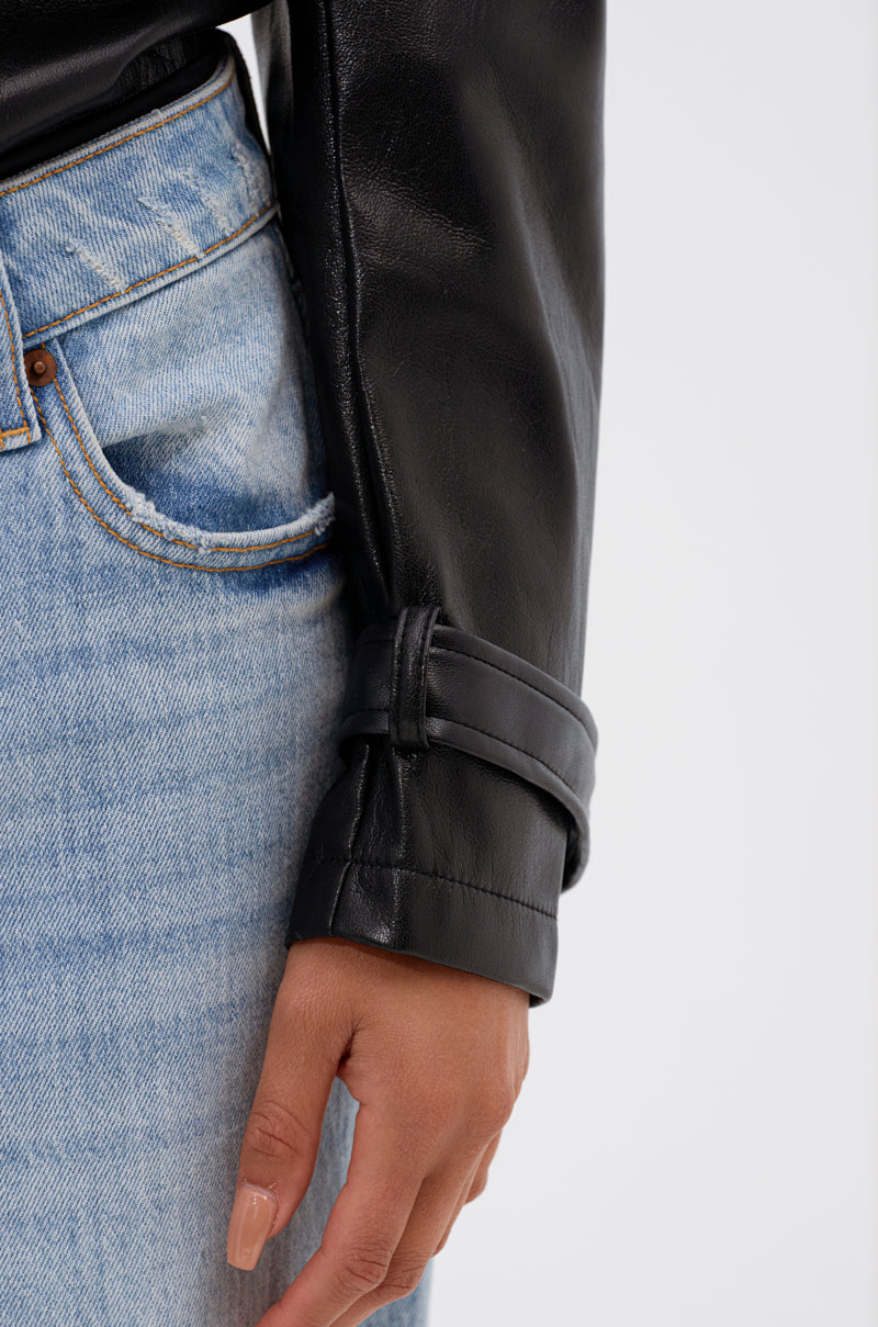 A close-up shows someone in light blue jeans and the TRACIE FAUX LEATHER BLAZER BODYSUIT. Their hand rests near their hip, and the black blazer's sleeve features a strap detail at the cuff. 6