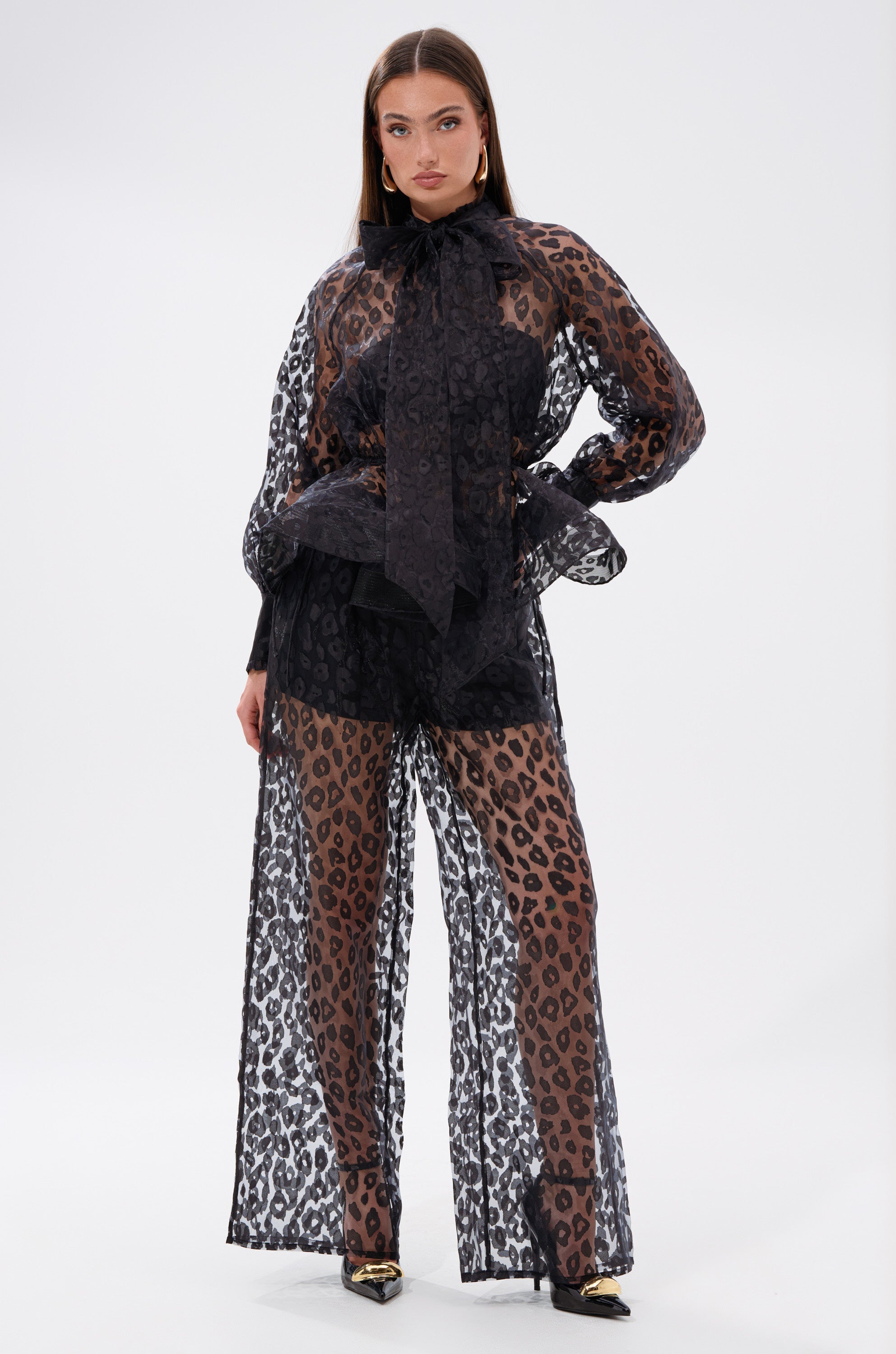 A woman in the CHEETAH SISTA PALAZZO PANT showcases a chic wide-leg silhouette with its high-rise fit and black outfit styling.