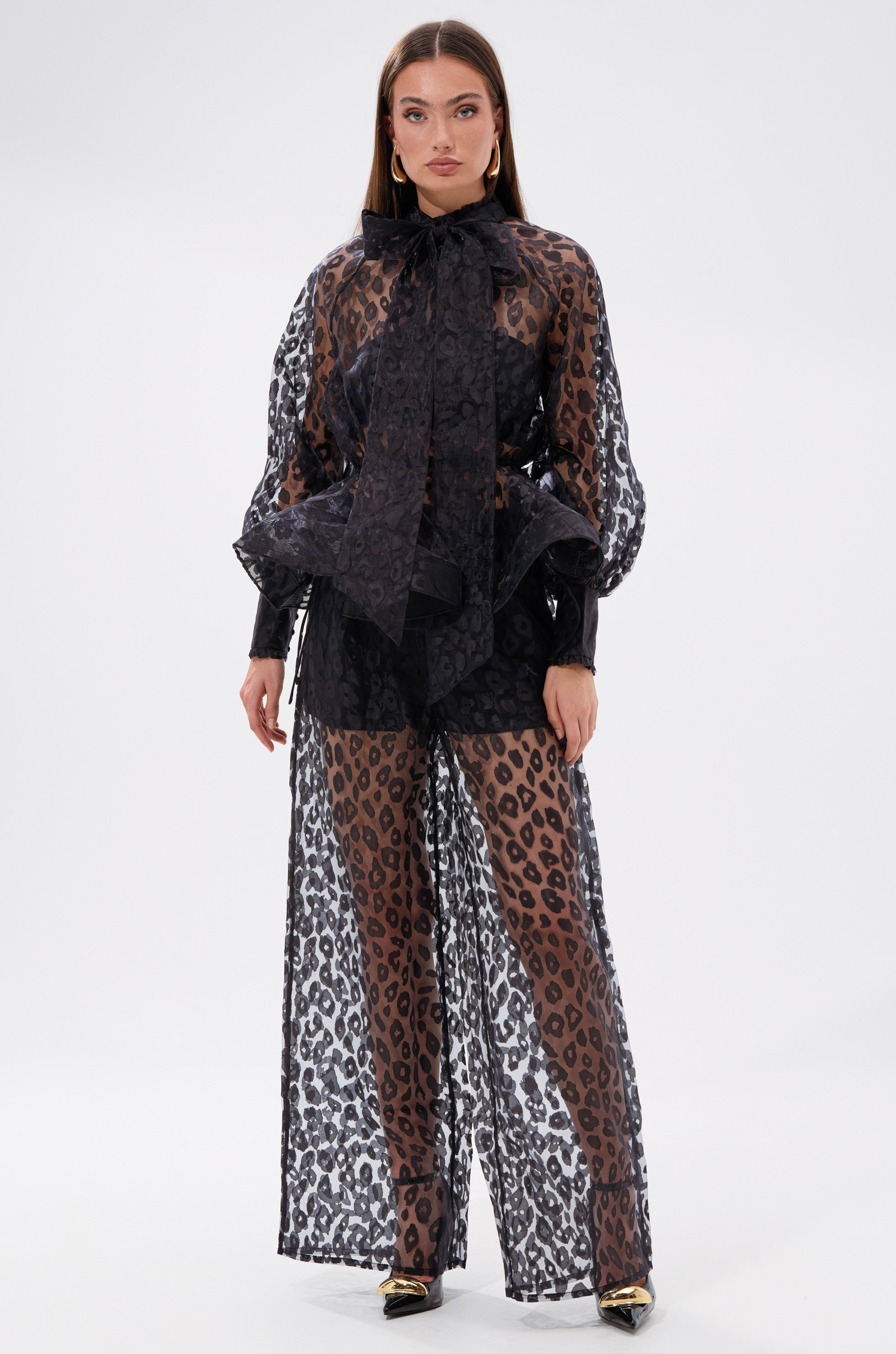 A woman styles the CHEETAH SISTA PALAZZO PANT with a black dress, achieving a bold and elegant look.