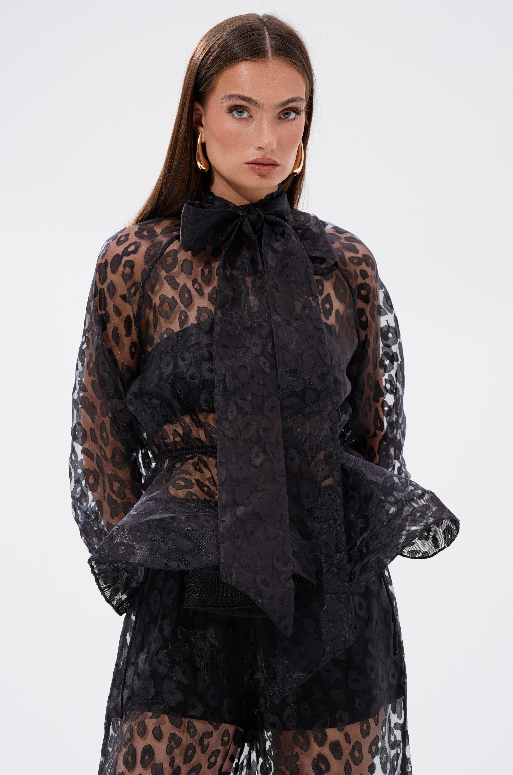 A woman in the CHEETAH SISTA TIE FRONT BLOUSE, featuring a chic peplum silhouette.