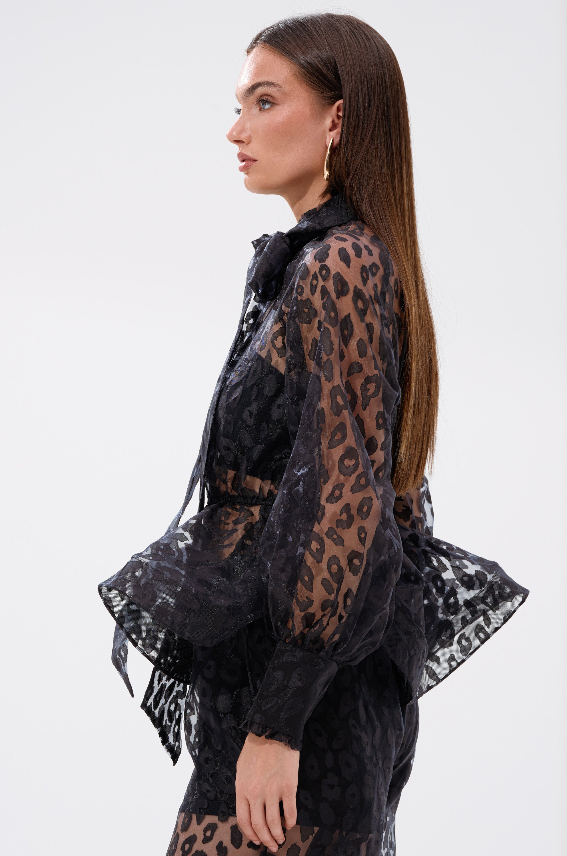 A woman wearing the CHEETAH SISTA TIE FRONT BLOUSE paired with a black dress.