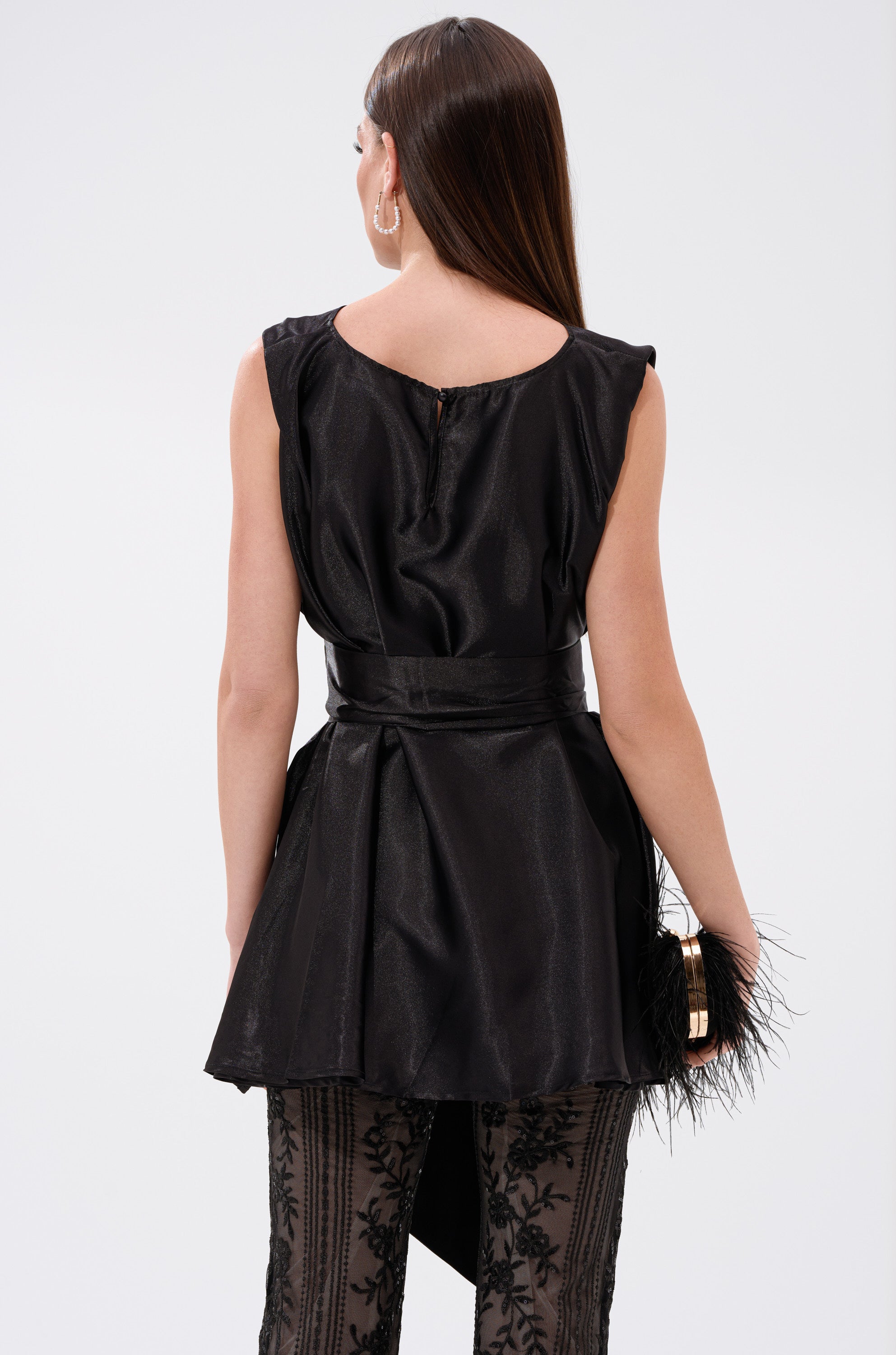 A woman wearing the DEZI SATIN BLOUSE, a sleeveless top, paired with a black dress.