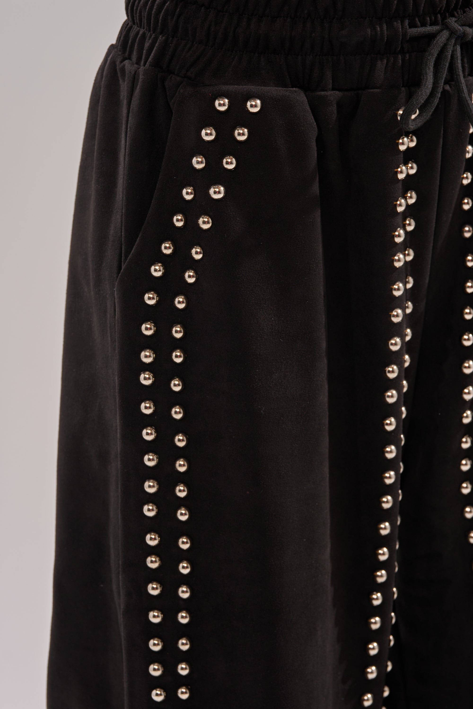 Close-up of the ASHLEY STUDDED WIDE LEG JOGGER in black velvet, featuring wide legs and decorative vertical rows of small metallic studs along the sides and pockets.