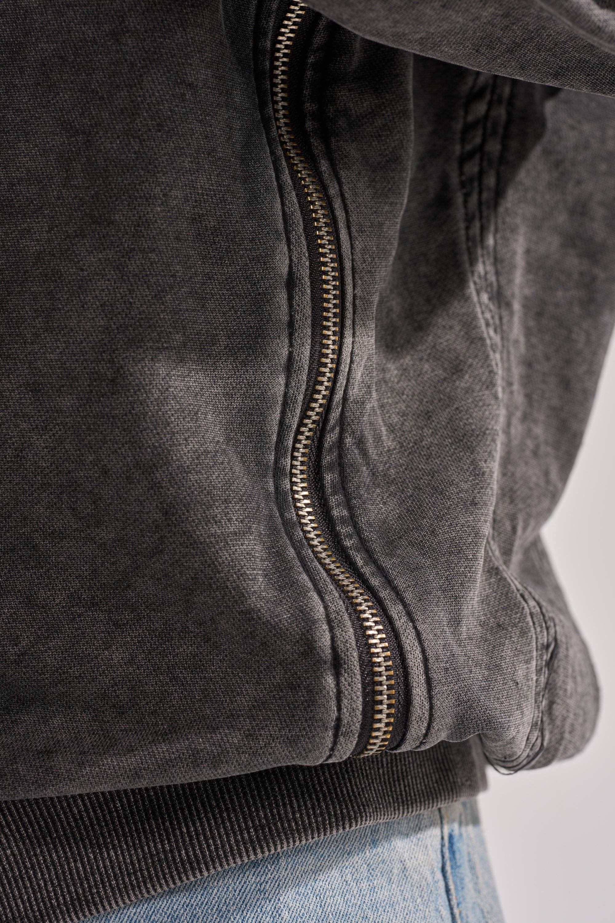 Close-up of the COOL GAL TIE SWEATSHIRT in charcoal, featuring a metallic zipper and paired with light blue jeans—ideal for loungewear.