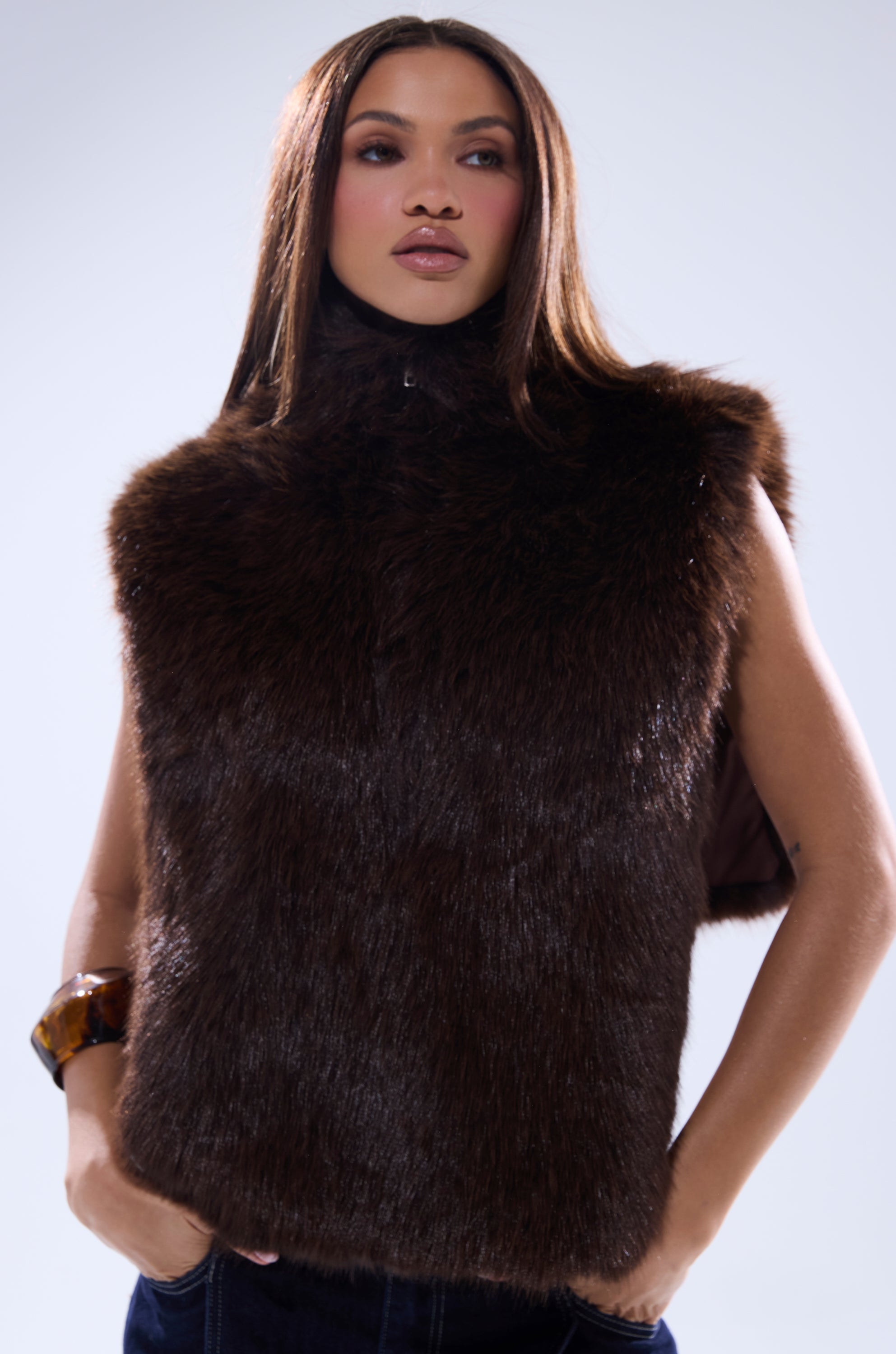 A woman with long straight hair models the SURE THANG FUR TURTLENECK PULLOVER, posing with her hands in her pockets against a plain light background. 3