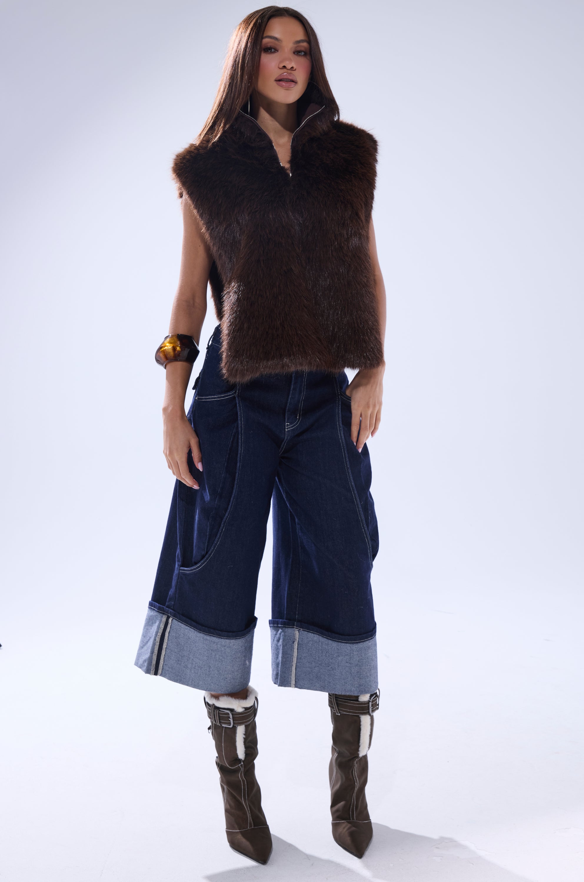 A woman poses in the SURE THANG FUR TURTLENECK PULLOVER, paired with wide-leg cuffed dark denim jeans, brown heeled boots, and a chunky bracelet, set against a plain light background. 7