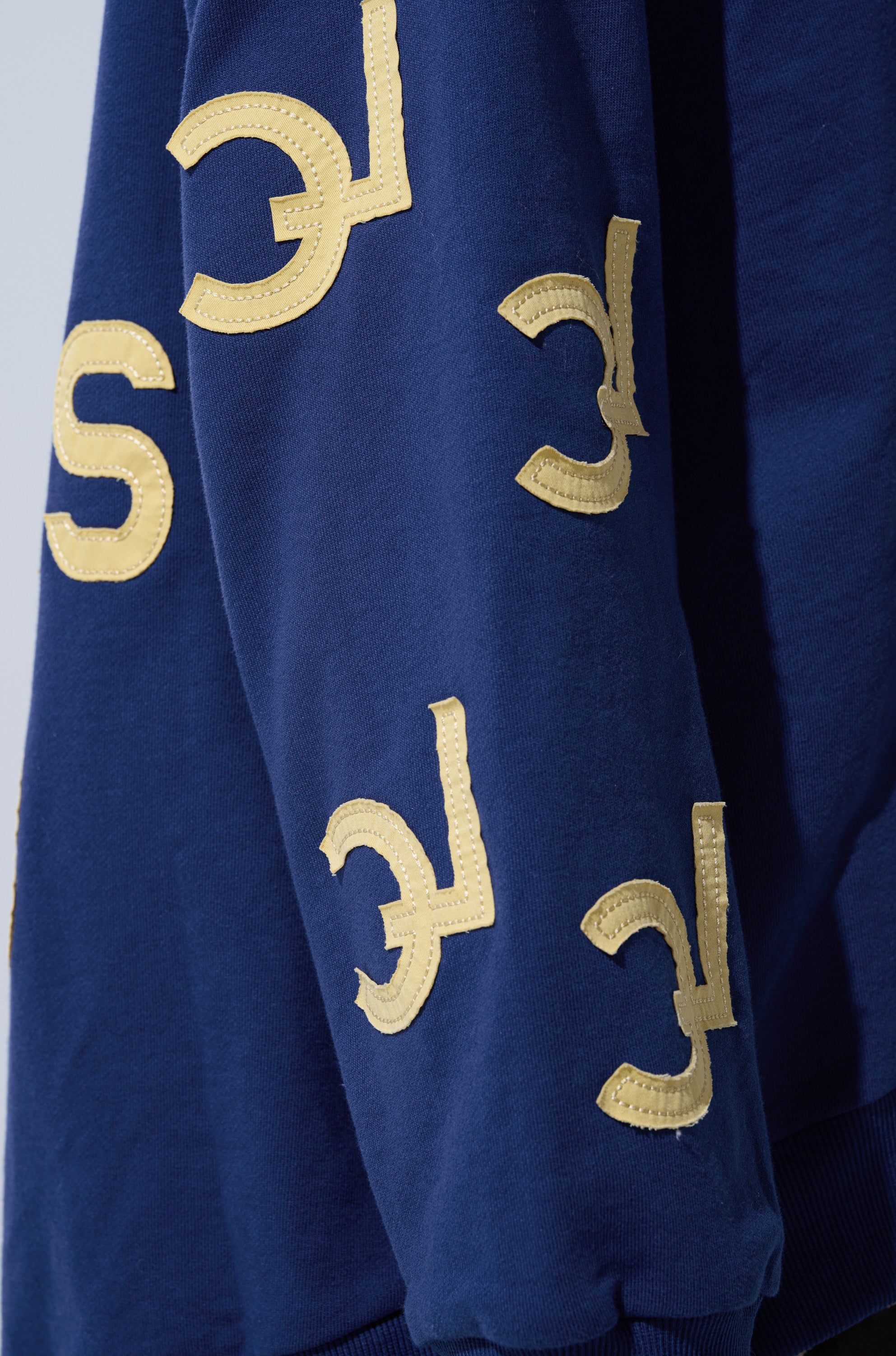 The CITY LOVER OVERSIZED SWEATSHIRT is a navy blue, cozy cotton-blend top for NYC lovers, detailed with multiple stitched yellow "C" and "E" letters in different orientations.