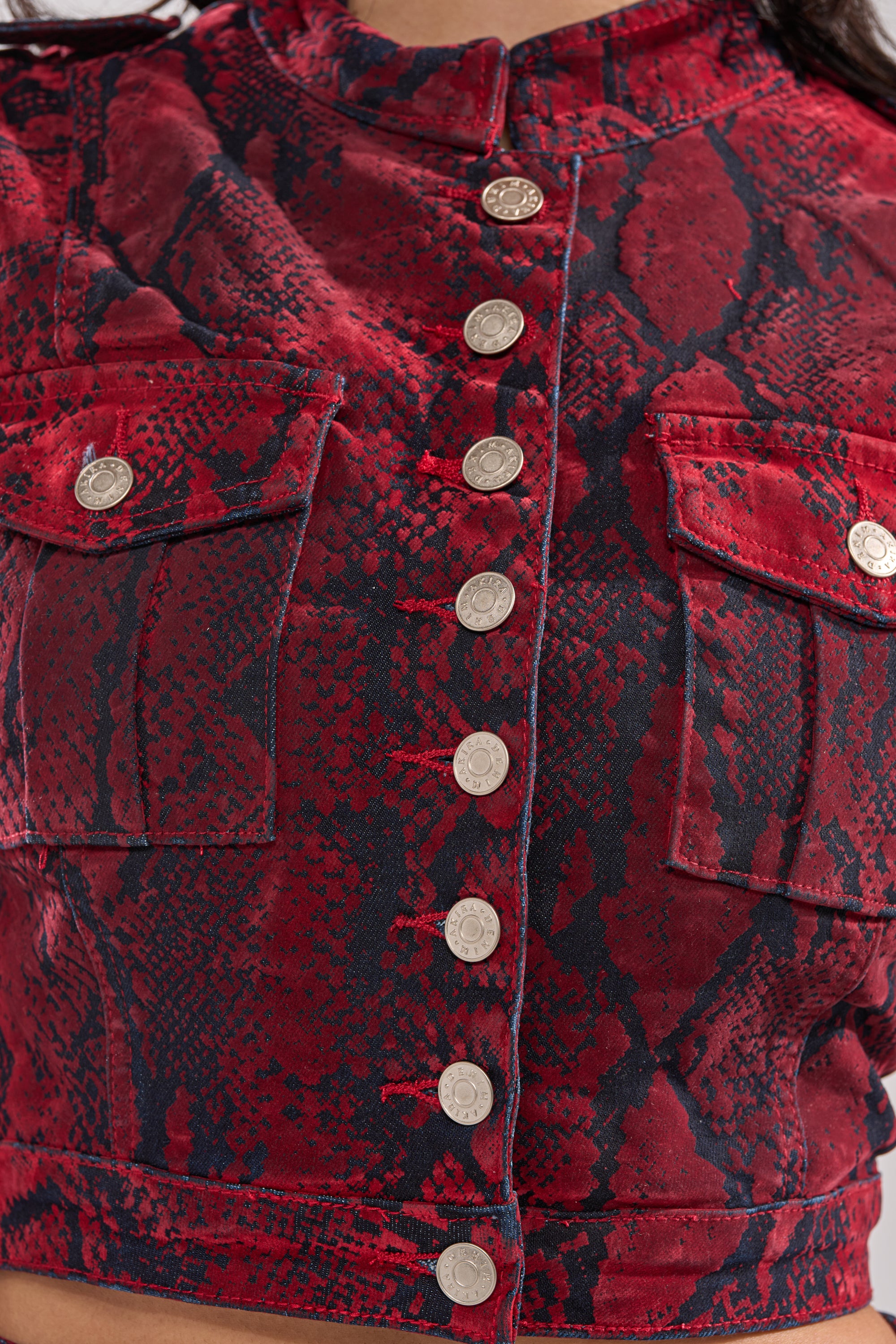 Close-up of the FLOATING IN BETWEEN SNAKE BUTTON DOWN, featuring a red and black snakeskin pattern, two chest pockets, and silver buttons down the front. 6