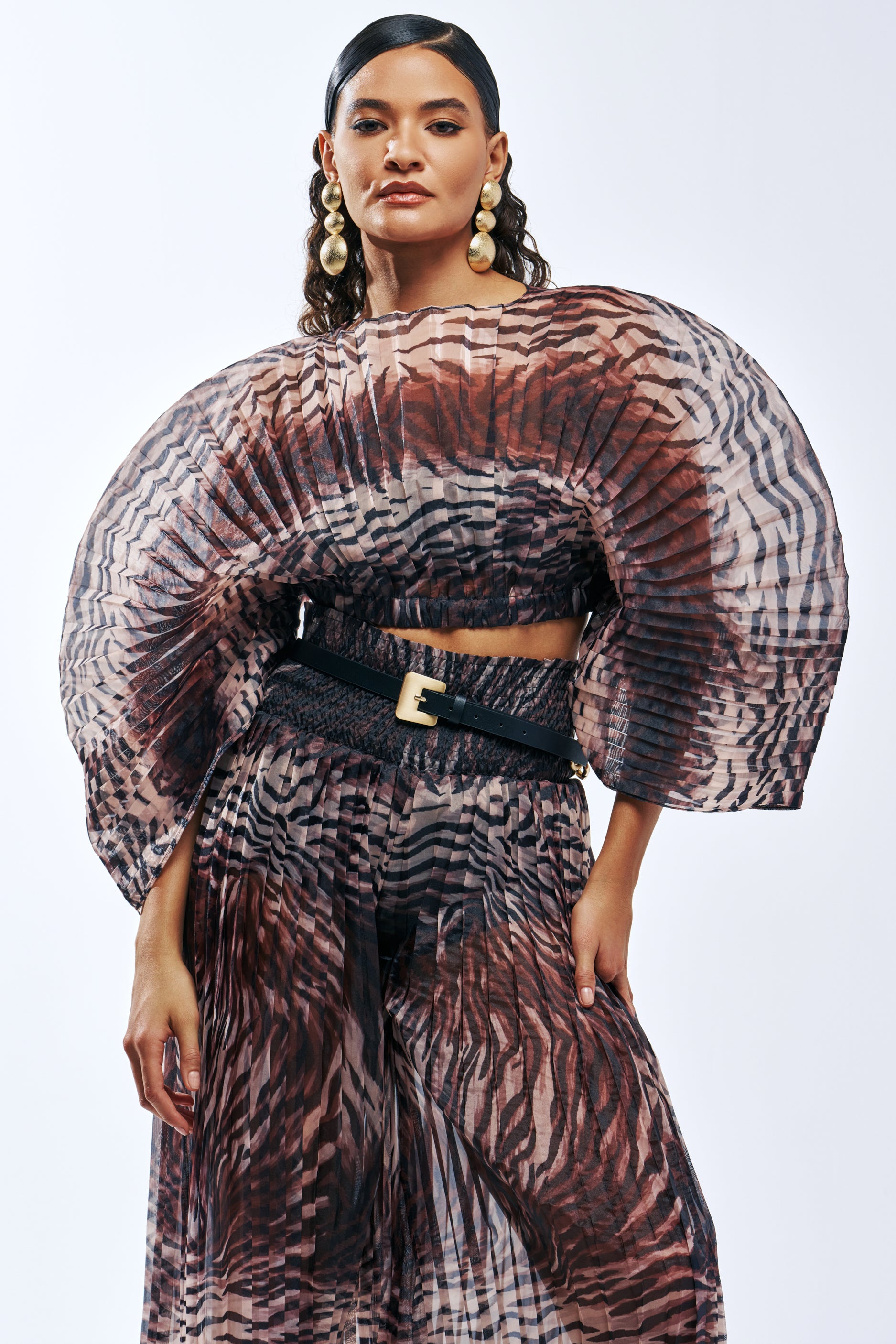 A person wears an ANGELINA ANIMAL PRINT PLEATED BLOUSE and matching skirt, featuring oversized puffed sleeves and a black belt.