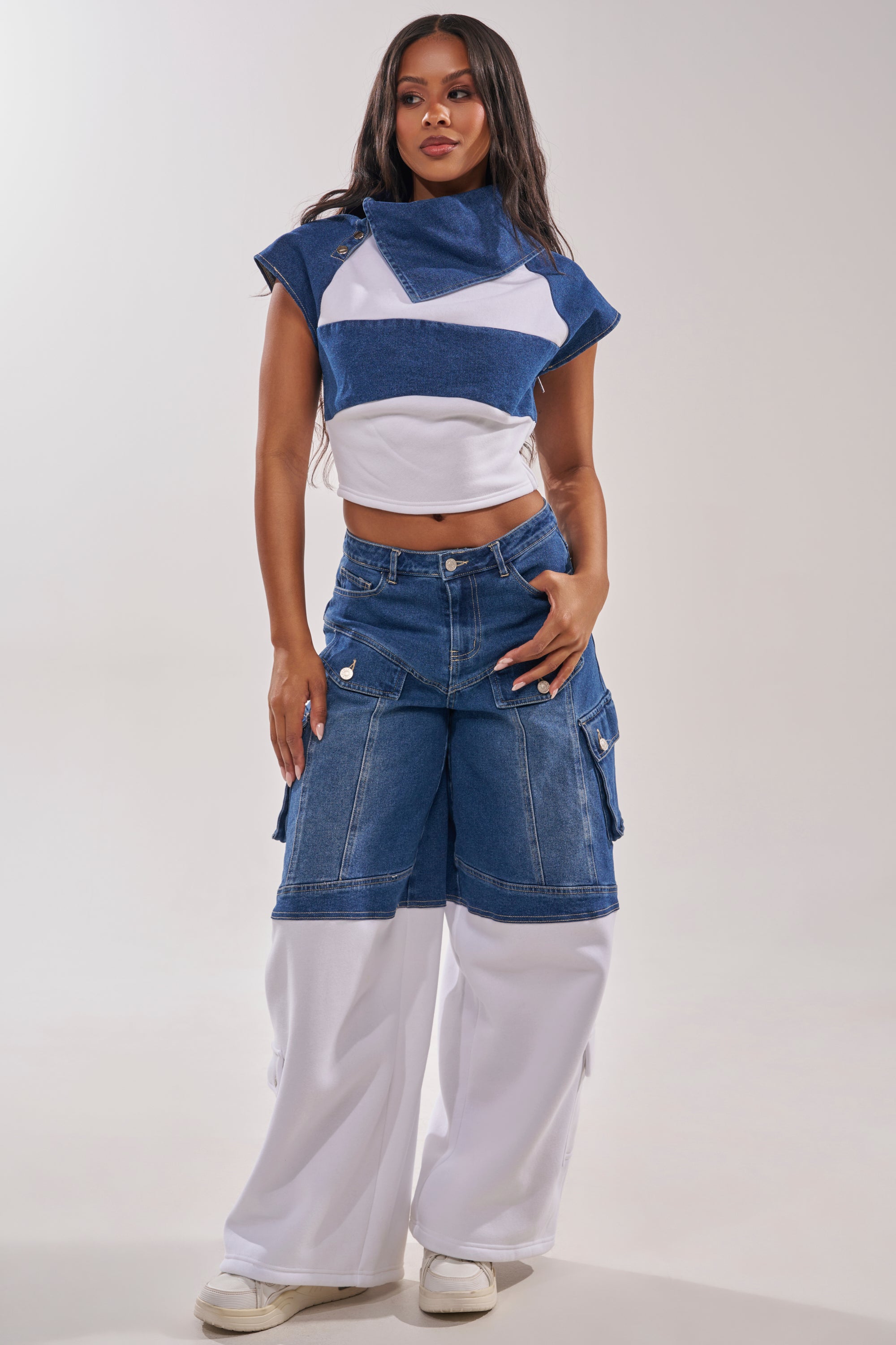 A woman stands confidently in THIS IS EVERYTHING YOU SEE RELAXED DENIM—blue and white color-blocked wide-leg cargo pants with a matching crop top and white sneakers—against a plain light background. 6