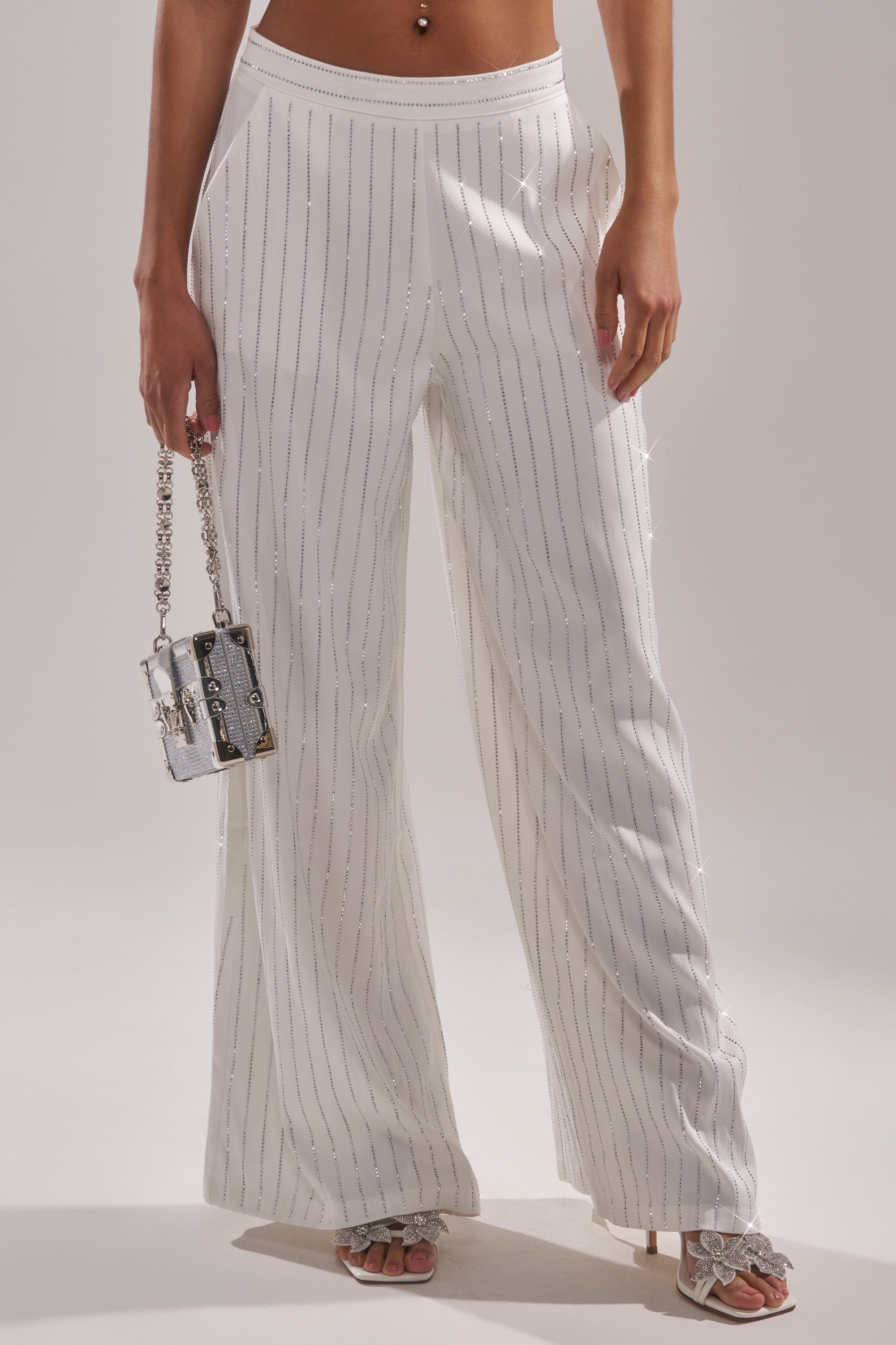 Wearing the PRINCESS TREATMENT RHINESTONE WIDE LEG PANT with silver stripes, this look shines with a small silver handbag and open-toe heeled sandals for true princess vibes. 1