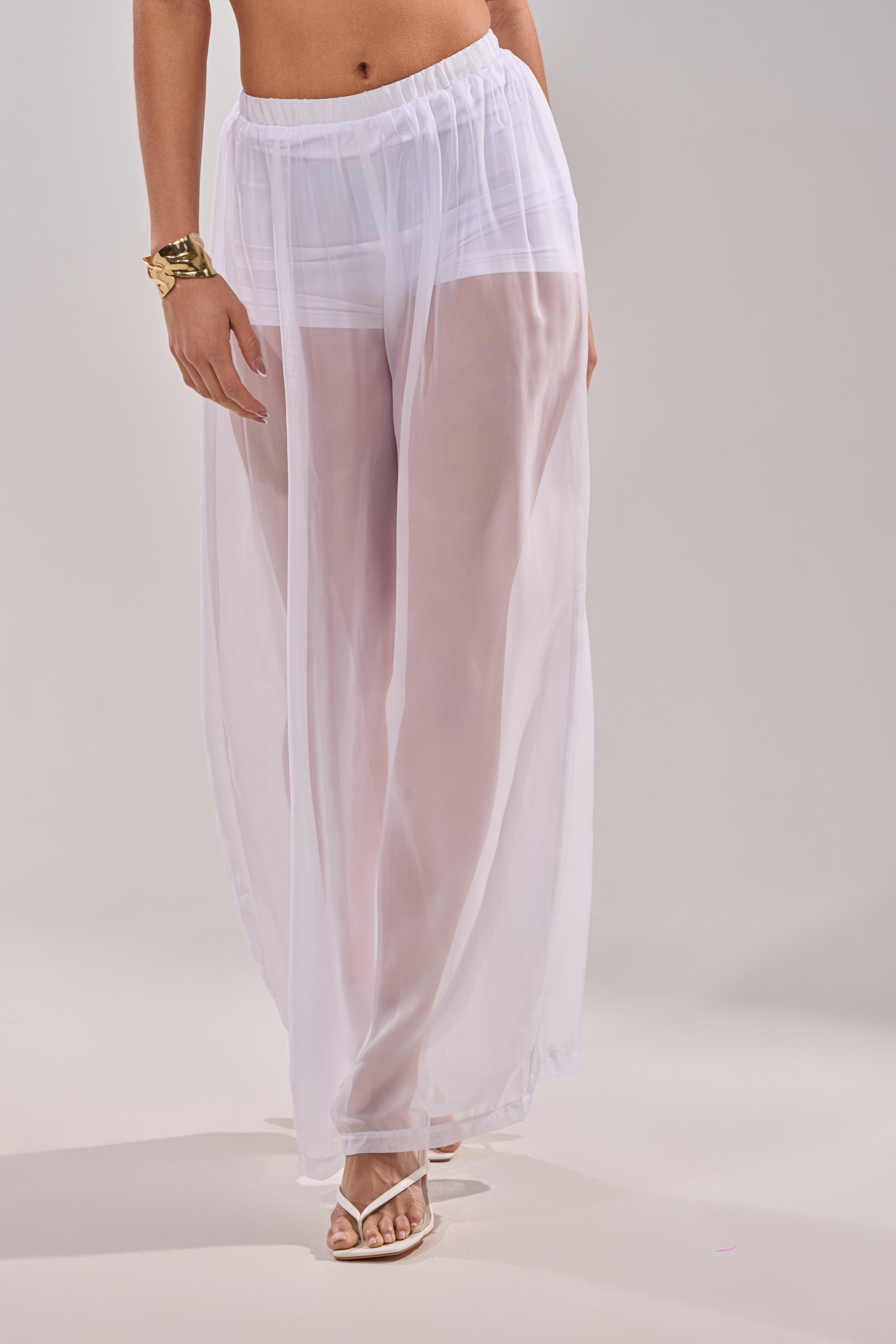 Wearing the DREAMY PALAZZO PANT over white shorts with a gold bracelet and white sandals, this look is poolside layering at its chicest against a simple backdrop. 3