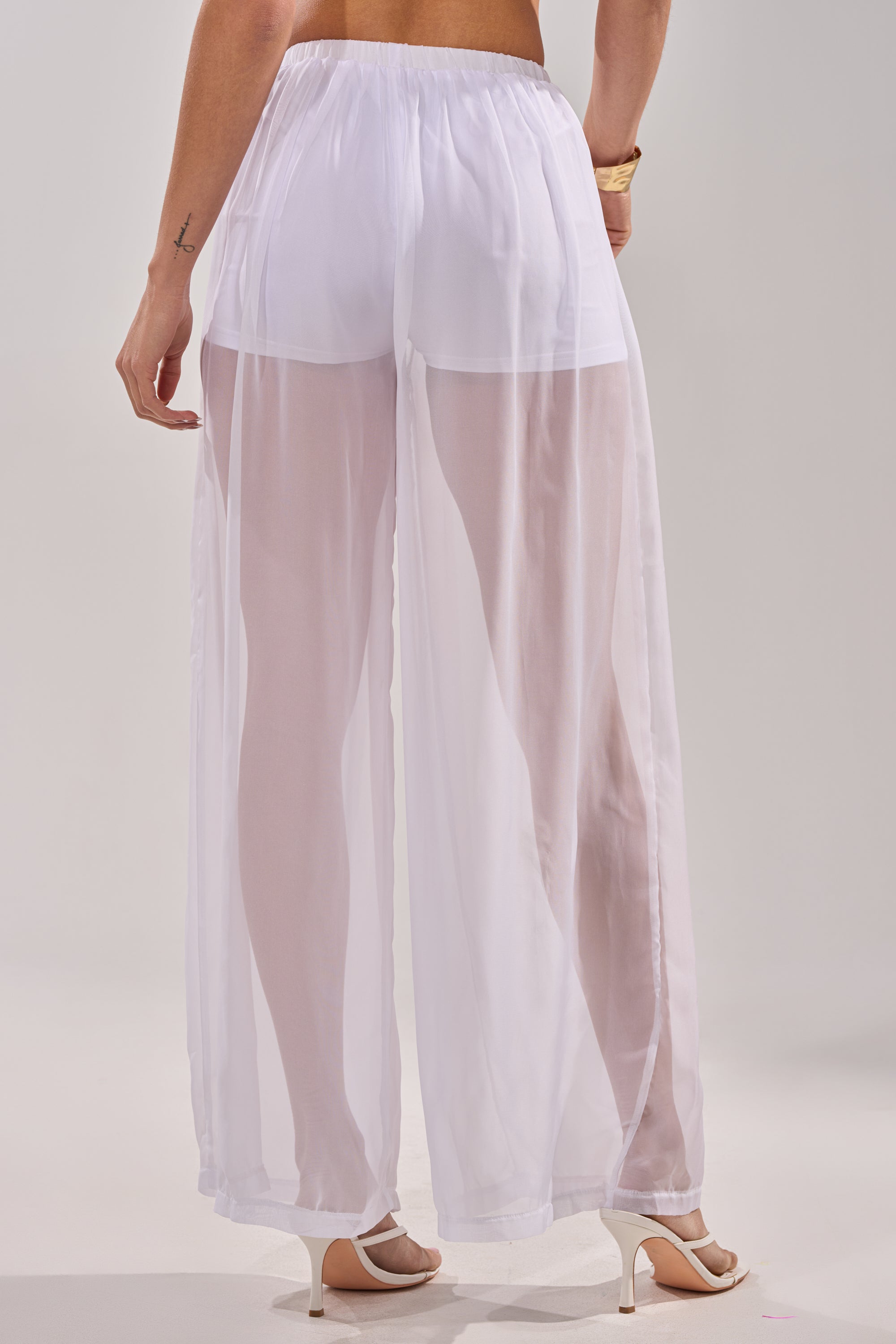 Wearing the DREAMY PALAZZO PANT cover up over white shorts and high-heeled sandals, a person stands with their back to the camera against a plain background. 5