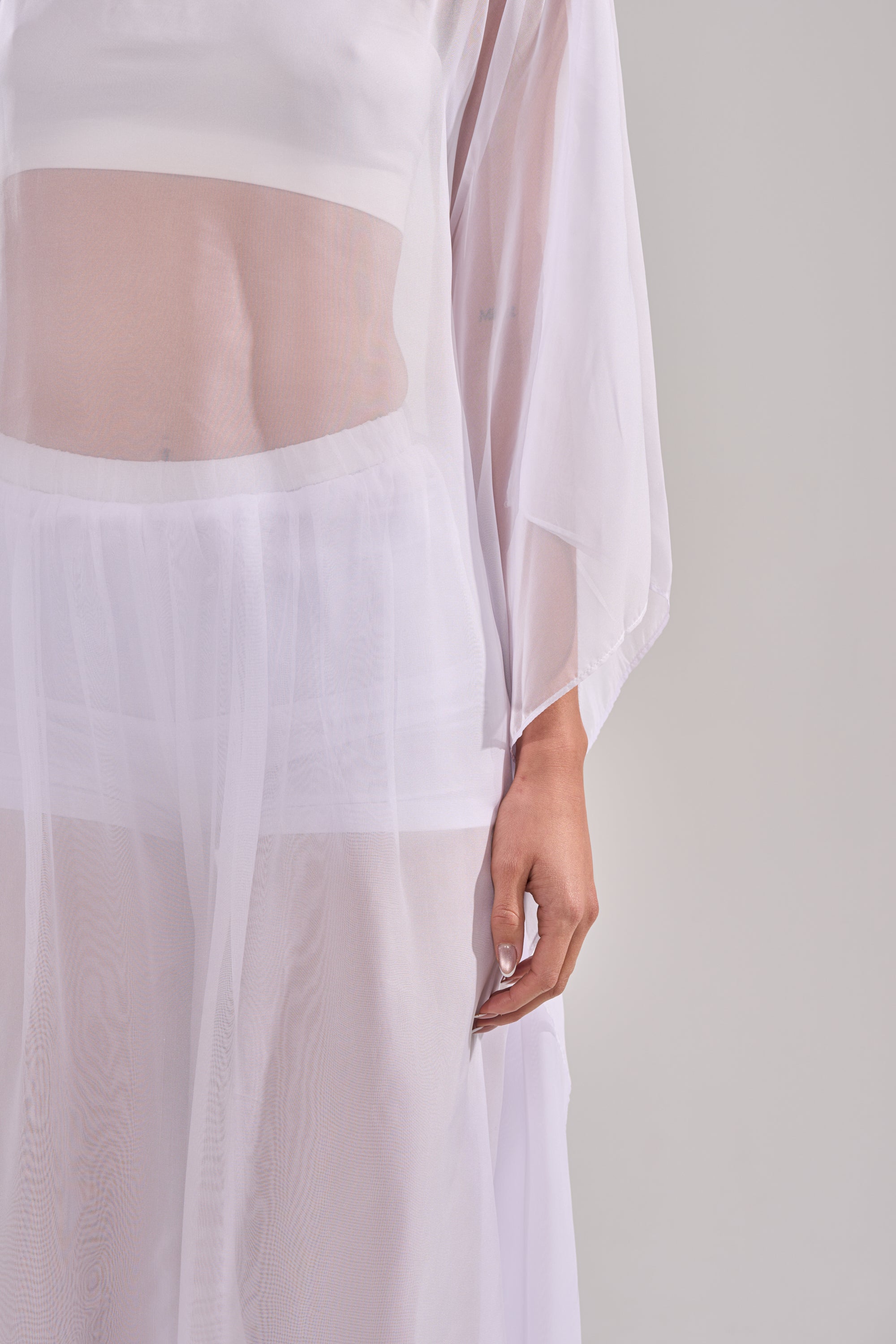 Wearing the DREAMY SHEER BLOUSE as a white, long-sleeved dress with visible undergarments, a person stands against a plain light gray background. Only their torso and one arm are shown. 9