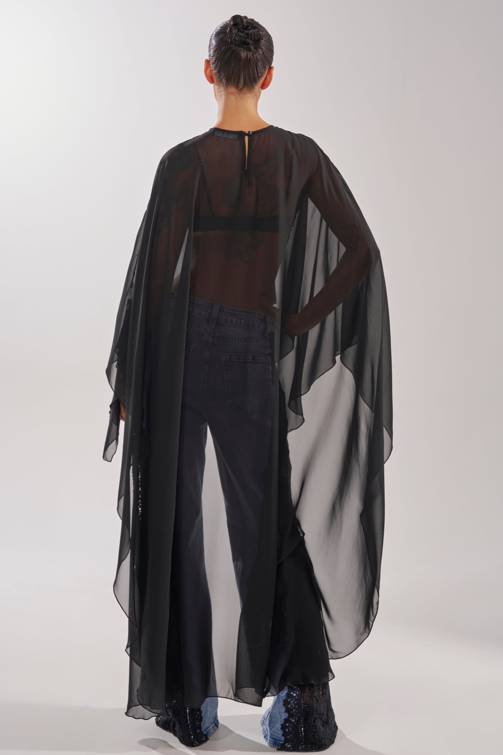 A woman in the COCO BLOUSE with black cape sleeves exudes elegance and mystery. 8