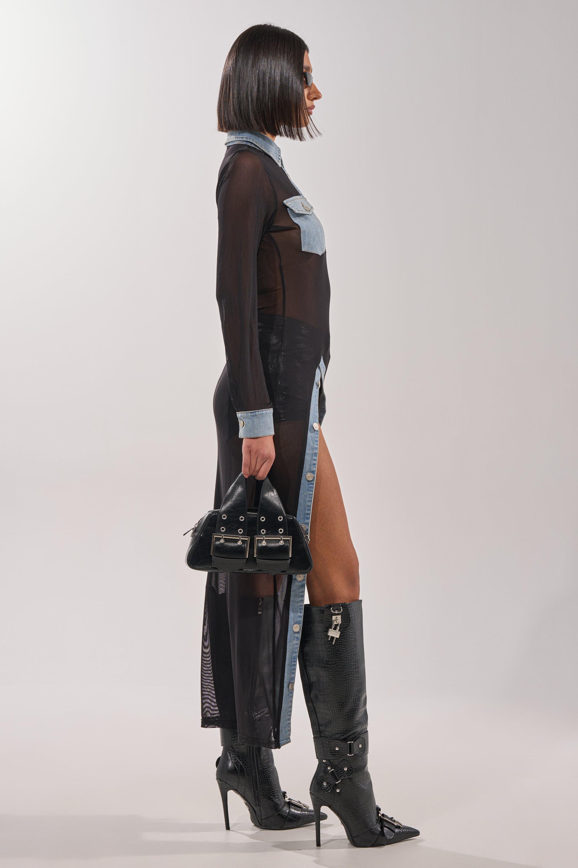 A woman wears the SABRINA LONG MESH BUTTON DOWN TOP styled in layers, carrying a purse with subtle denim accents completing her look. 5