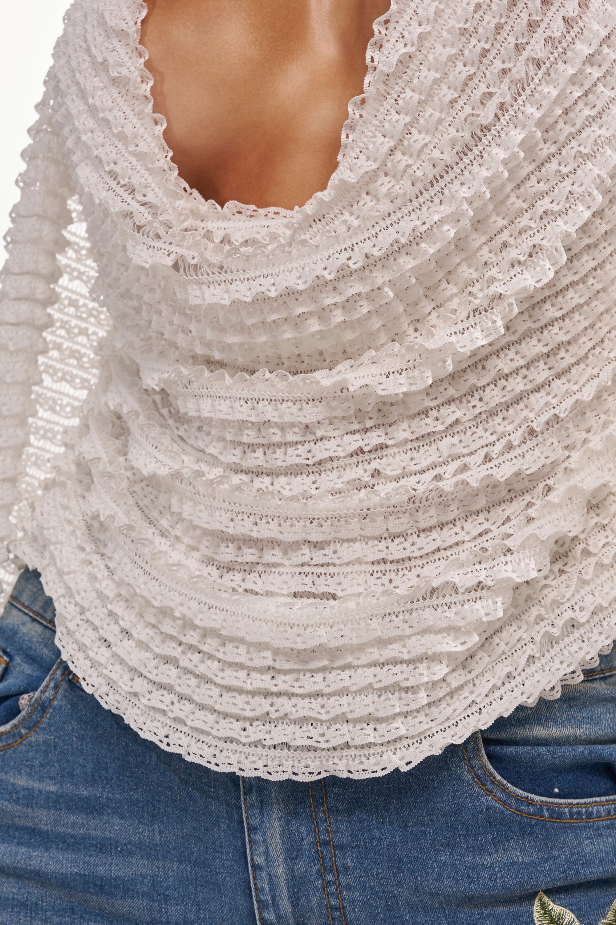 A close-up of a person wearing the TAKE ME TO THE TROPICS COWL NECK BLOUSE with blue denim jeans. Only the torso is visible—ideal for creating a chic beach vacation style. 7