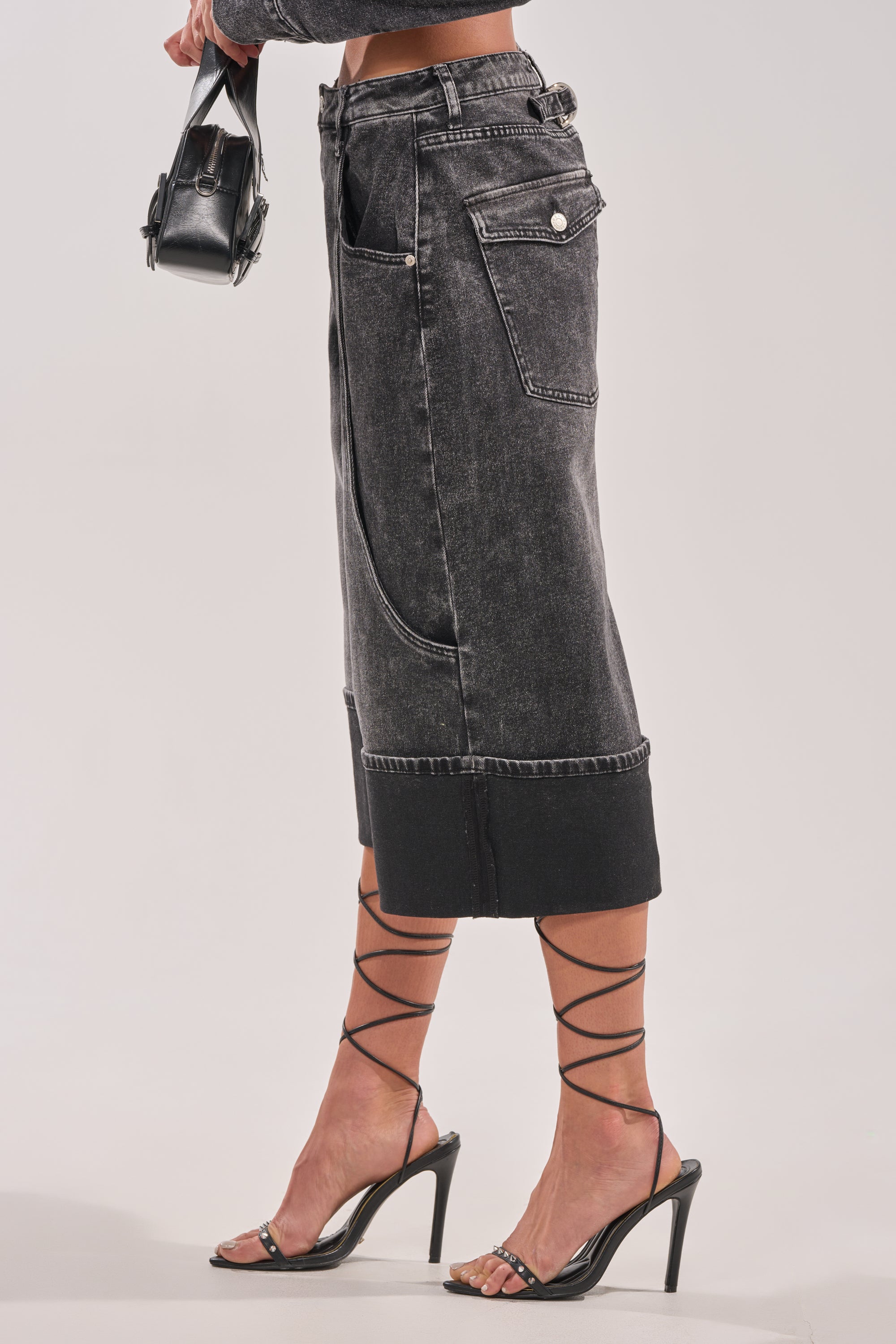 A person wearing the IN MY OWN WORLD BERMUDA SHORT, strappy black high-heeled sandals, and carrying a small black handbag against a plain background. 3