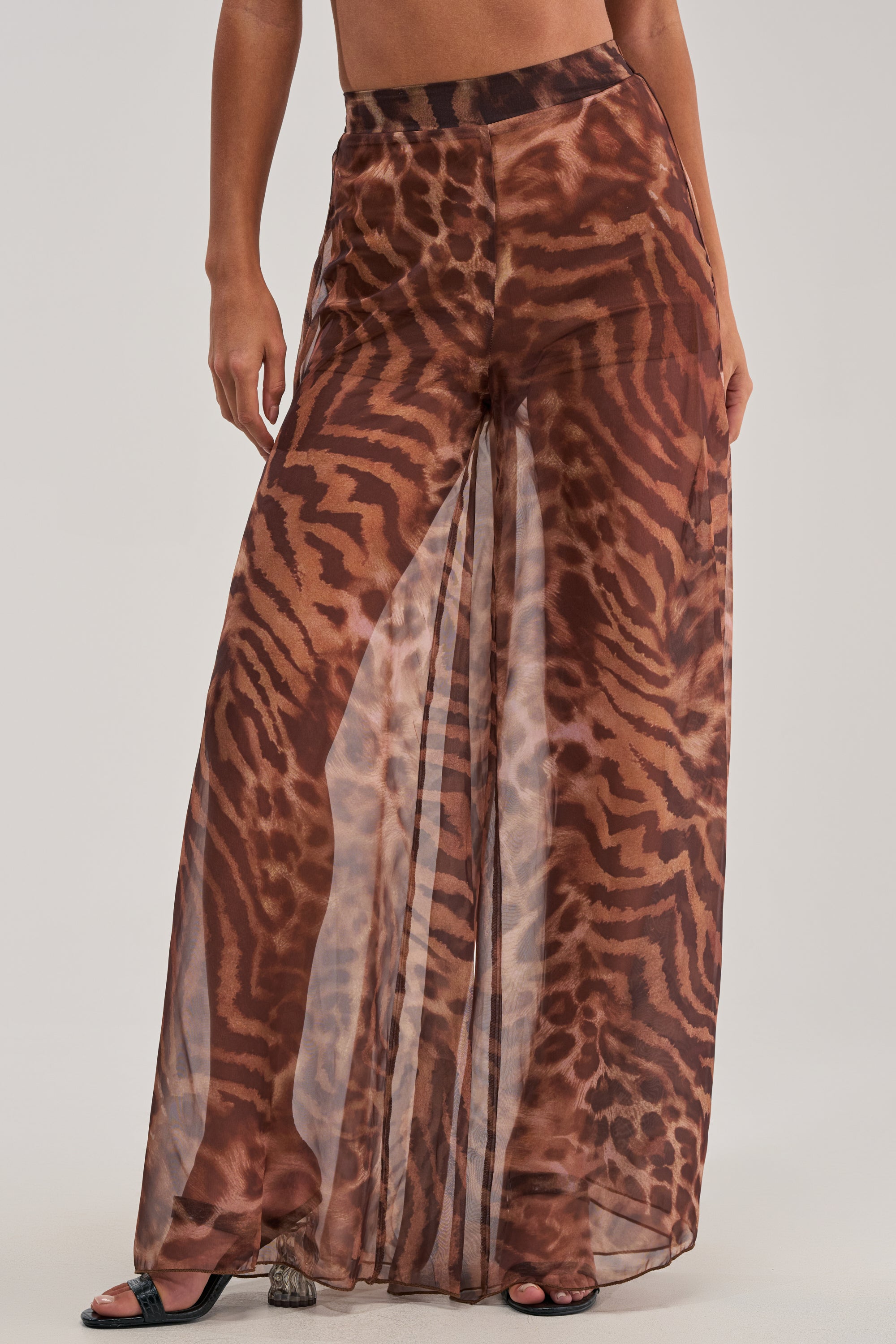 A person wears MOONLIGHT TIGER PALAZZO PANTS—sheer, wide-leg pants with a brown and black tiger stripe pattern over matching shorts. Only the lower body is visible.
