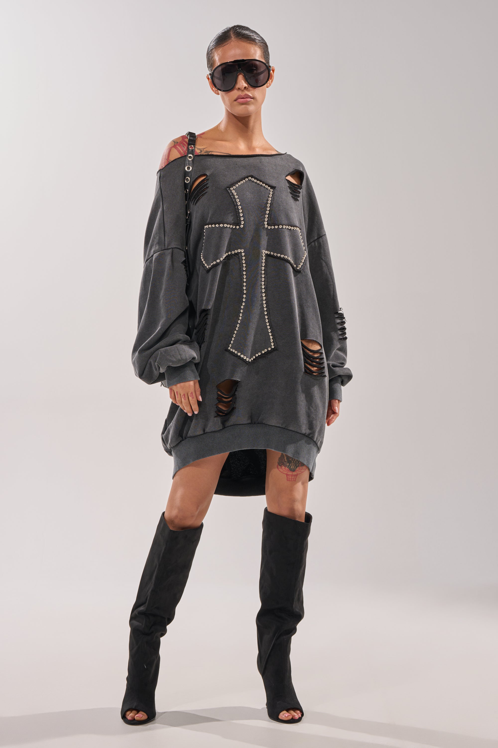 A woman in dark sunglasses and the LEX STUDDED MINI SWEATSHIRT DRESS with black knee-high heeled boots stands confidently against a plain background. 7