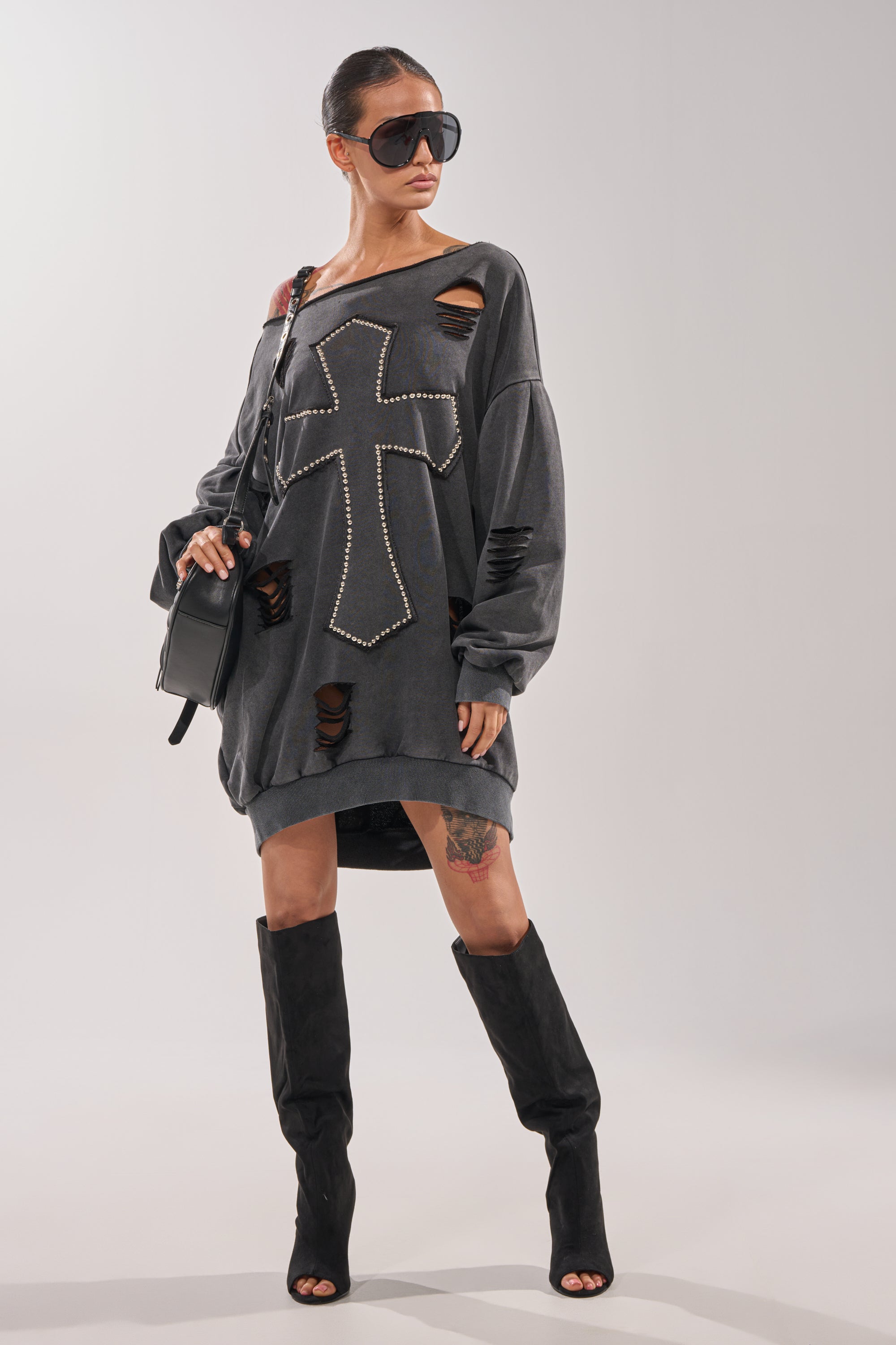 A woman stands confidently against a plain background wearing the LEX STUDDED MINI SWEATSHIRT DRESS, black peep-toe boots, large sunglasses, and a black shoulder bag. 8