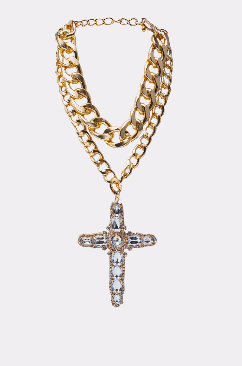 The LOVER LAYERED NECKLACE features three thick gold Cuban chain links and a jeweled cross pendant encrusted with clear gemstones, displayed on a plain white background.