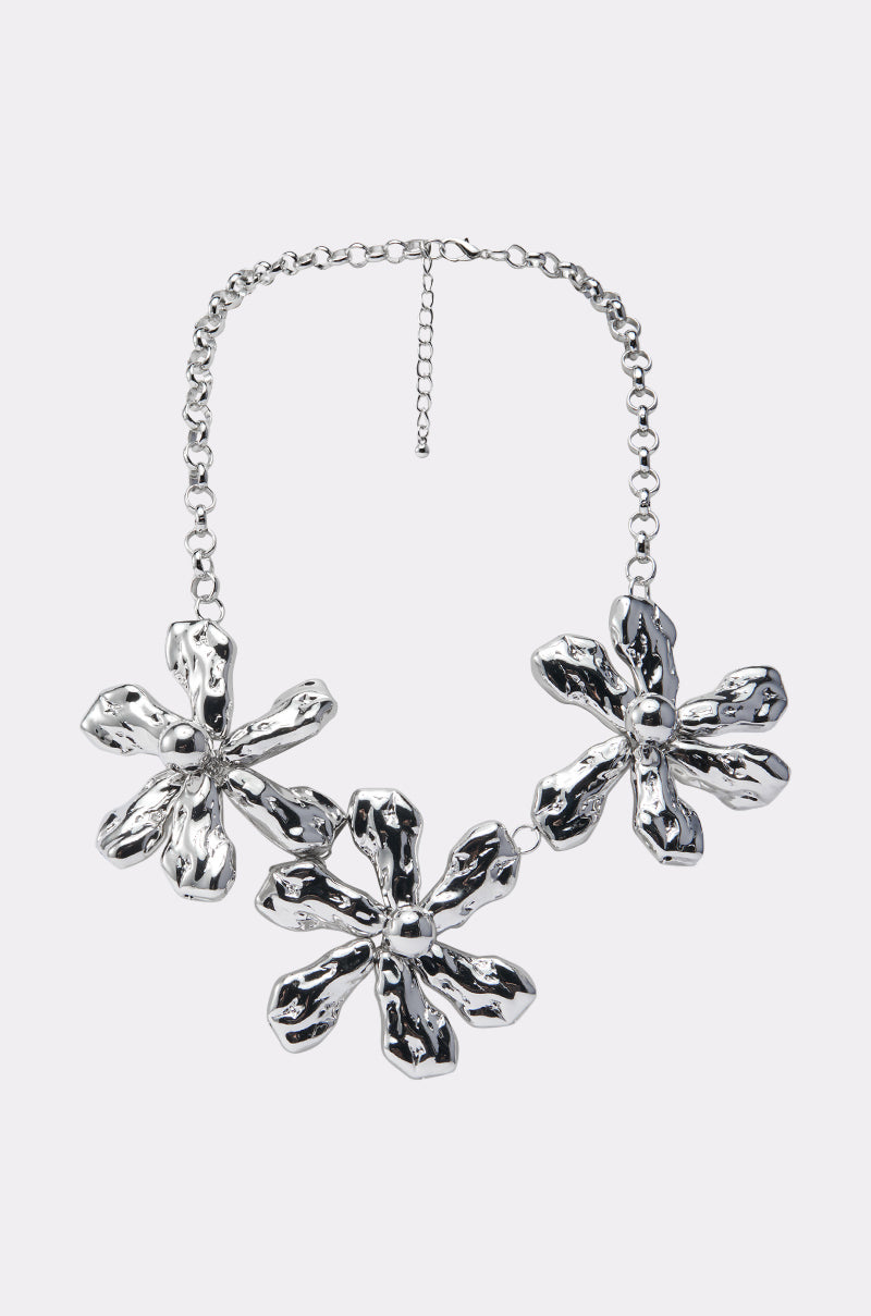 The BELLI NECKLACE is a chunky silver piece featuring three large, abstract flower-shaped pendants on a chain with an adjustable clasp—a stunning statement accessory.