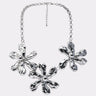 The BELLI NECKLACE is a chunky silver piece featuring three large, abstract flower-shaped pendants on a chain with an adjustable clasp—a stunning statement accessory.
