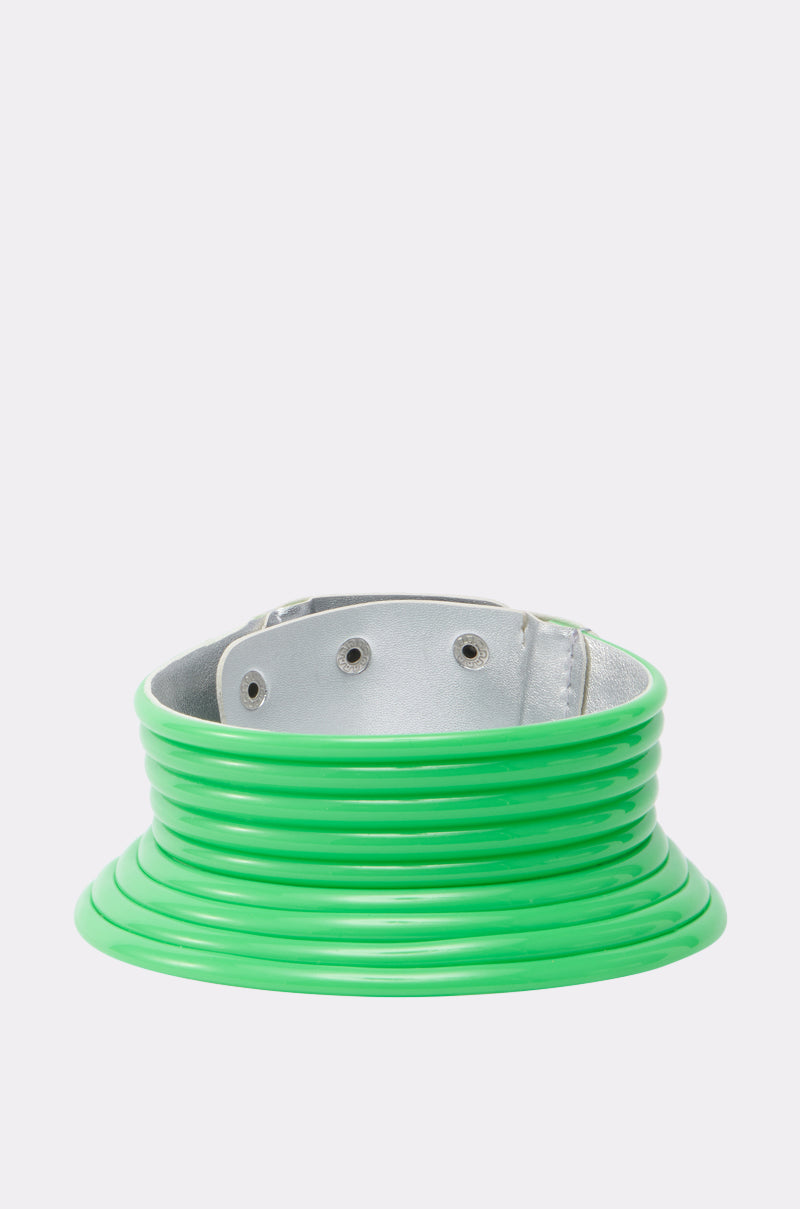 The TOO BRAT NECKLACE is a wide metallic silver statement piece, featuring layered glossy neon green coil-like rings that add a futuristic flair when displayed on a plain white background. 0