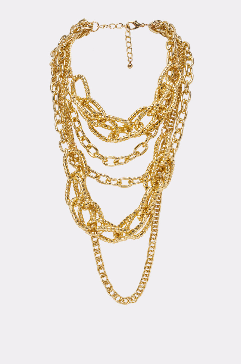 The LAYERS ON LAYERS NECKLACE showcases a gold-tone, multi-strand design with varying link sizes and a secure clasp—making it the perfect statement piece for any occasion.