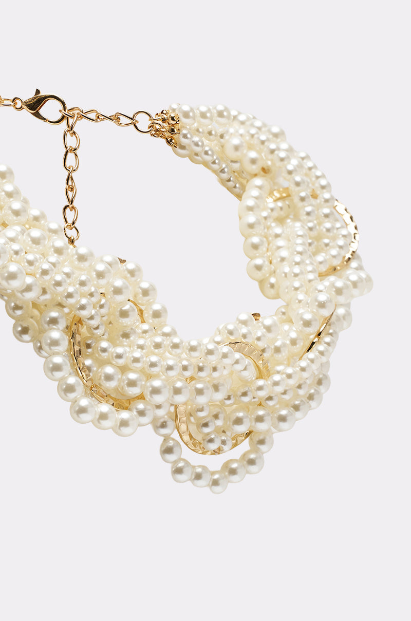 The SHARON NECKLACE is a multi-strand piece with twisted small white faux pearls braided together, gold-tone links, and a gold lobster clasp, shown close-up against a plain light background. 4