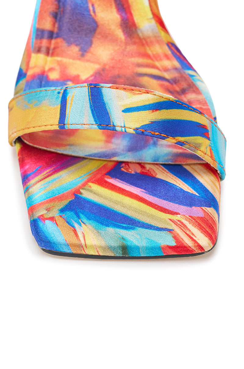 Close-up of the AZALEA WANG JOHA ORANGE MULTI PRINTED SATIN WRAP UP STILETTO, an open-toe sandal with vibrant blue, yellow, orange, and red abstract patterns and elegant wraparound satin straps. 6