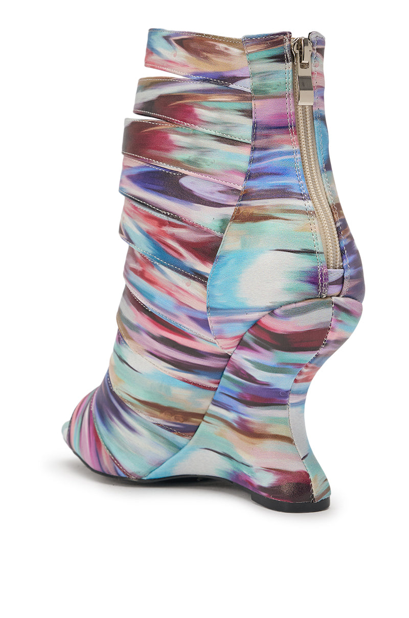 The AZALEA WANG JOHANNES MULTI RAINBOW WEDGE OPEN TOE BOOTIE features abstract, colorful fabric in blue, purple, pink, brown, and tan swirls with a sculpted curved wedge heel and side zipper, shown from the back. 5
