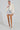 A person wearing the Jolene Faux Fur Coat in white over a silver sequined dress and white platform heels stands against a plain background. Their hair is styled back, exuding confidence and style.