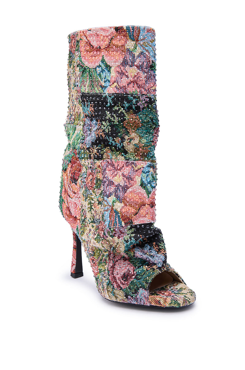 The AZALEA WANG JONICE FLORAL RHINESTONE EMBELLISHED OPEN TOE BOOTIE features high heels, an open toe, a slouchy shaft, and a vibrant floral tapestry in pink, green, blue, and black shades.
