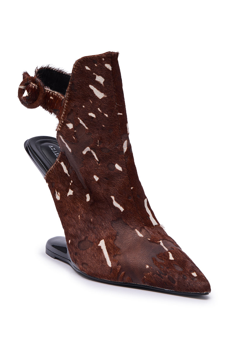 The AZALEA WANG JOST BROWN MULTI WEDGE PUMP is a pointed-toe, backless ankle boot with a brown and white calf hair upper, black sole, and a distinctive round fur accent at the ankle.