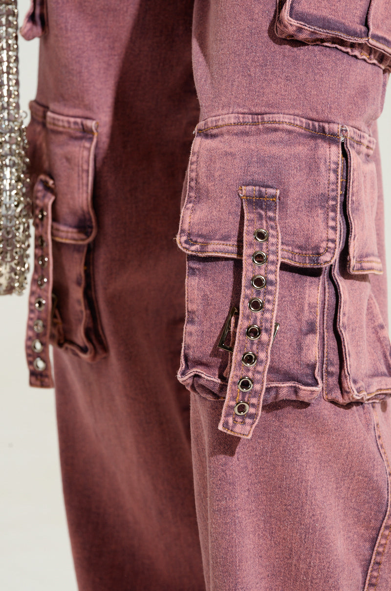 Detailed view of the ACID WASHED DENIM JUMPSUIT in mauve, featuring multiple pockets and metallic eyelet detailing. The fabric exhibits a textured, slightly worn appearance, enhancing its vintage charm.
