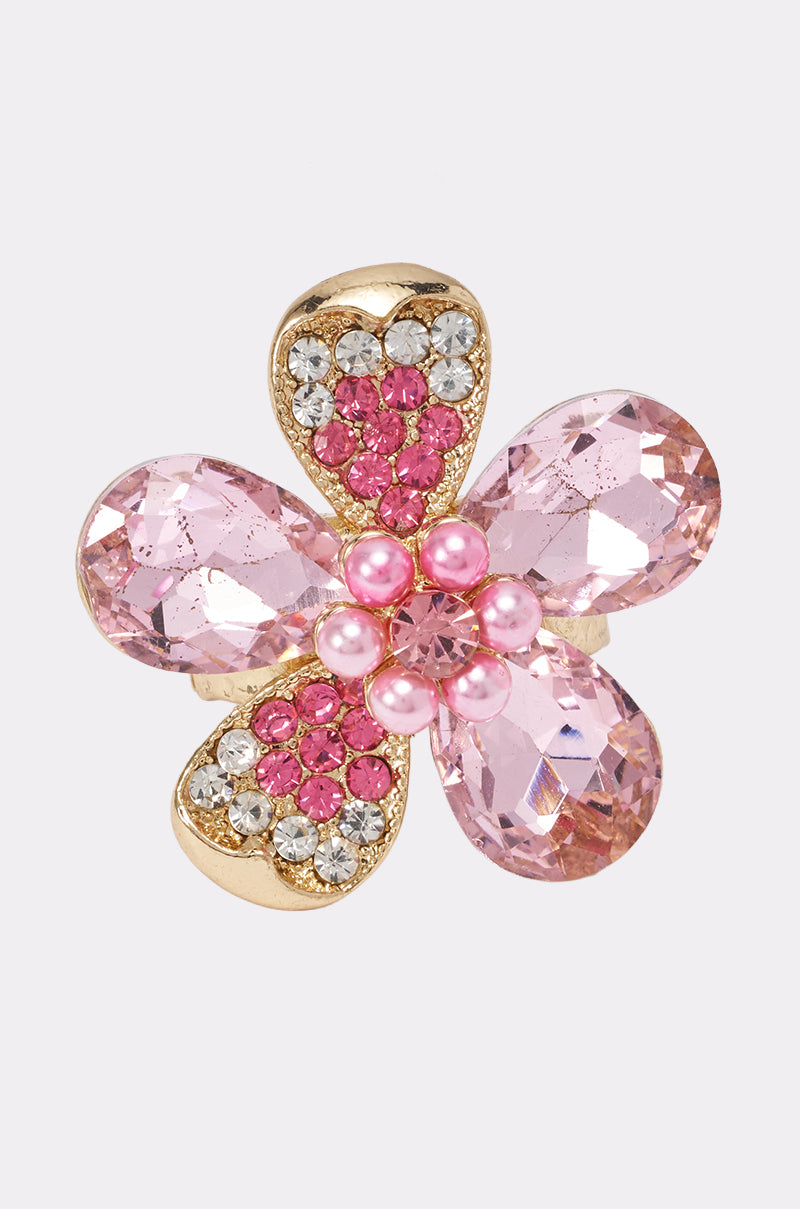 Introducing the BLOSSOM RING: a stunning gold stretch band ring designed in the shape of a flower. Each petal sparkles with pink rhinestones, while pink pearls form the elegant centerpiece and shimmering clear crystals accentuate the petals. This comfortable and stylish accessory is perfect for anyone looking for a unique pink floral ring that combines beauty with ease of wear.