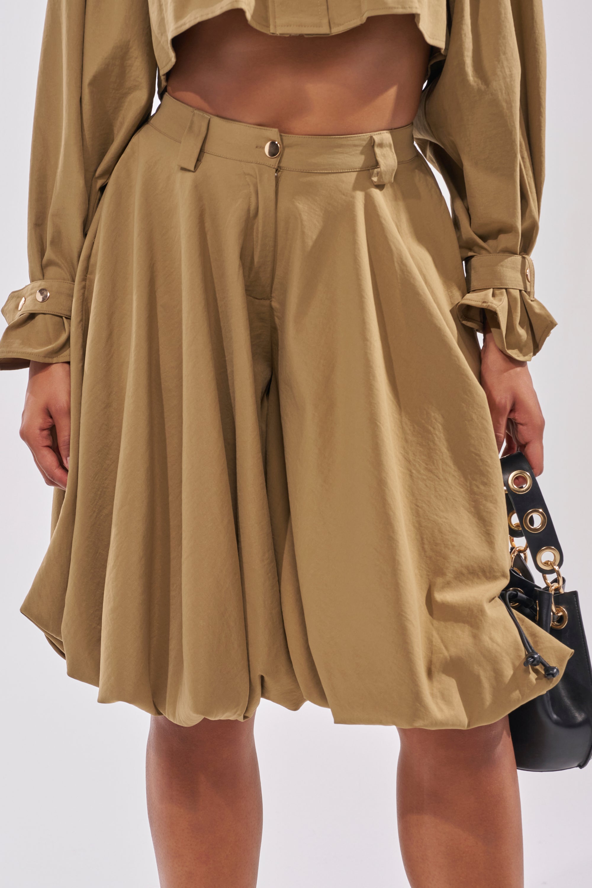 Wearing tan CANT STOP WONT STOP BERMUDA SHORTS with a matching cropped top for an oversized, structured look, accessorized with a black handbag featuring metal eyelets. 8
