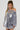 A person with braided hair is wearing the GEMMA Off The Shoulder Voluminous Sequin Mini Dress in Silver. They are standing against a neutral background, looking slightly to the side.