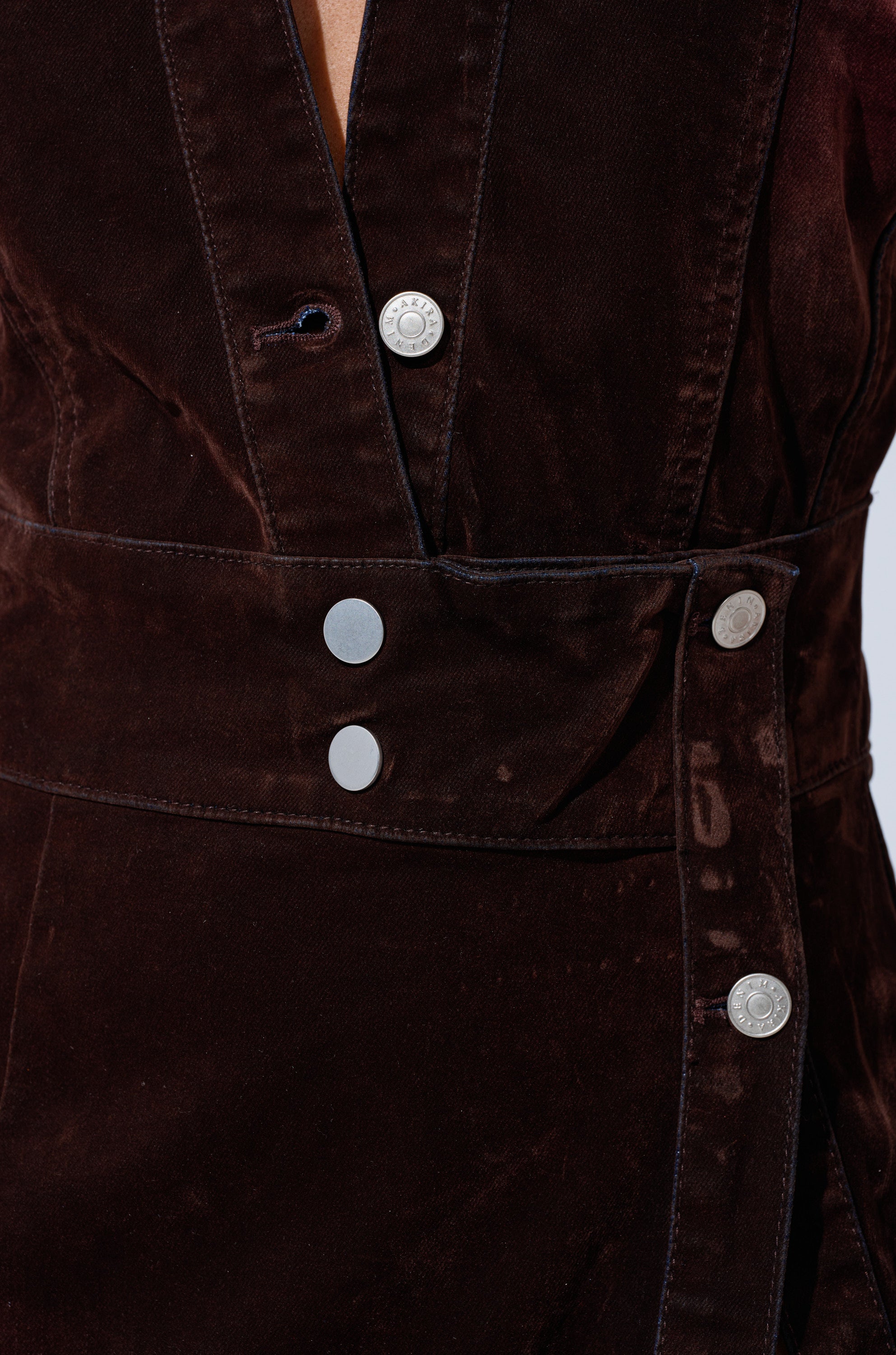 Close-up of the CHELSEA BUTTON DOWN MAXI DRESS IN VELVET DENIM, featuring dark brown velvet denim, metallic buttons, a wide matching belt at the waist, and visible texture with detailed stitching.