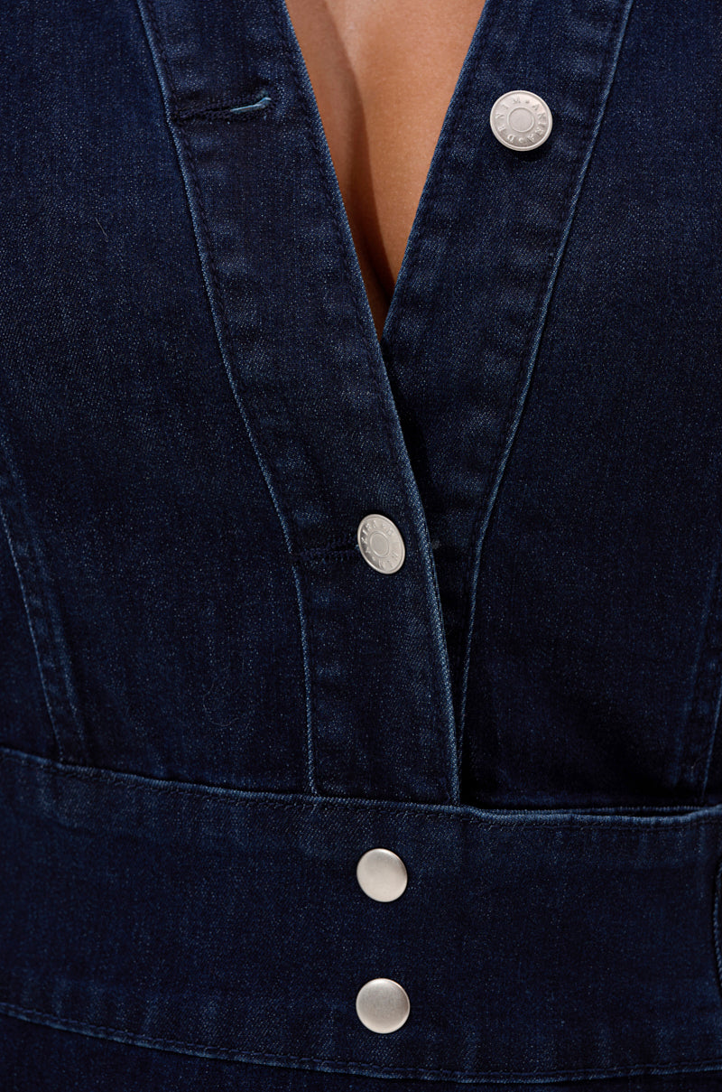 Close-up of the CHELSEA BUTTON SIDE DENIM MAXI DRESS in dark wash, featuring silver snap buttons, a deep V-neckline, visible seams, and thick structured fabric.