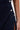 Close-up of a person's arm and hip wearing the CHELSEA BUTTON SIDE DENIM MAXI DRESS, featuring silver buttons, a side slit, visible seams, and buttonholes that highlight its textured denim and detailed construction.
