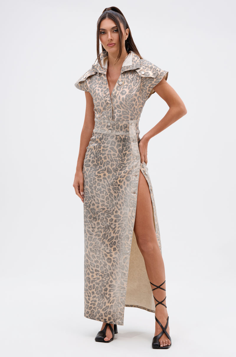 A woman models the TOO BUSY TO CARE LEOPARD MIDI DRESS, featuring beige and grey leopard print, short sleeves, a popped collar, high side slit, and curve-hugging fit. She pairs it with black strappy sandals against a plain background.