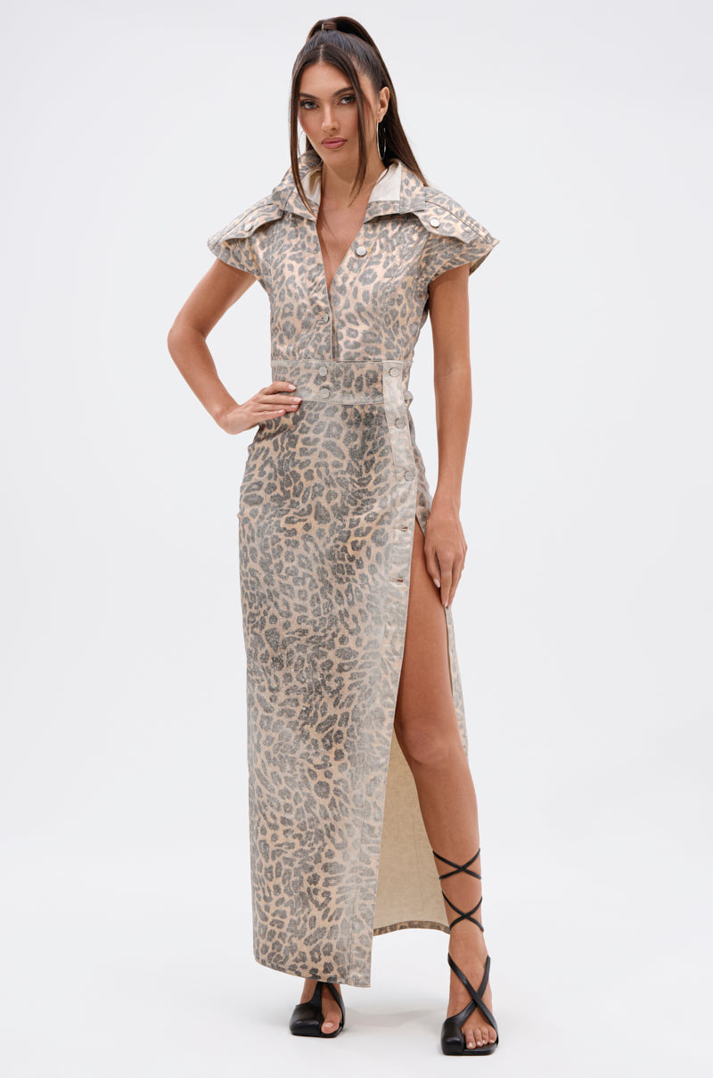 A woman wears the TOO BUSY TO CARE LEOPARD MIDI DRESS, featuring a curve-hugging fit, wide collar, and high thigh slit. She styles it with black strappy sandals, straight brown hair, and poses confidently against a plain background.