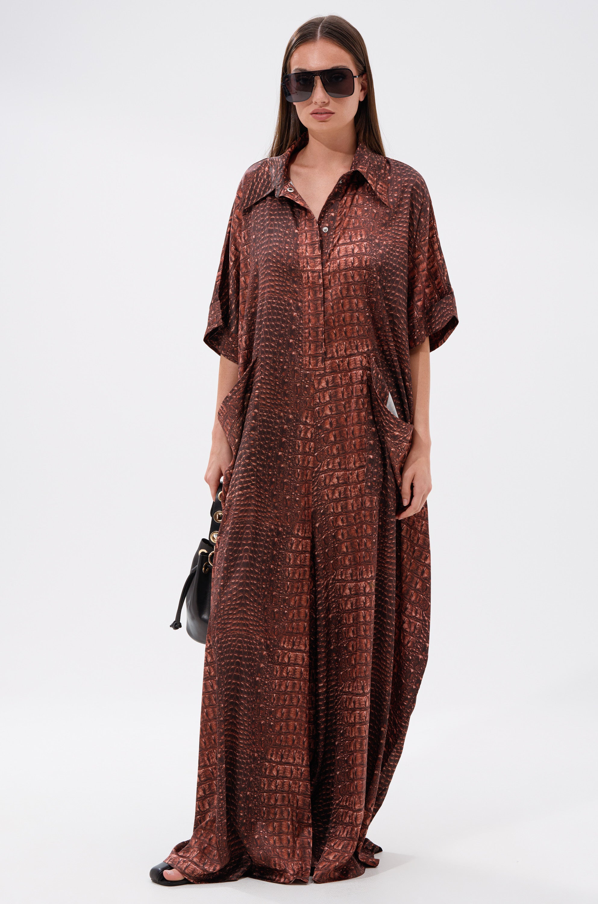 A woman in a long dress completes her look with the SHE'S RICH Oversized Satin Jumpsuit in Croc Print.